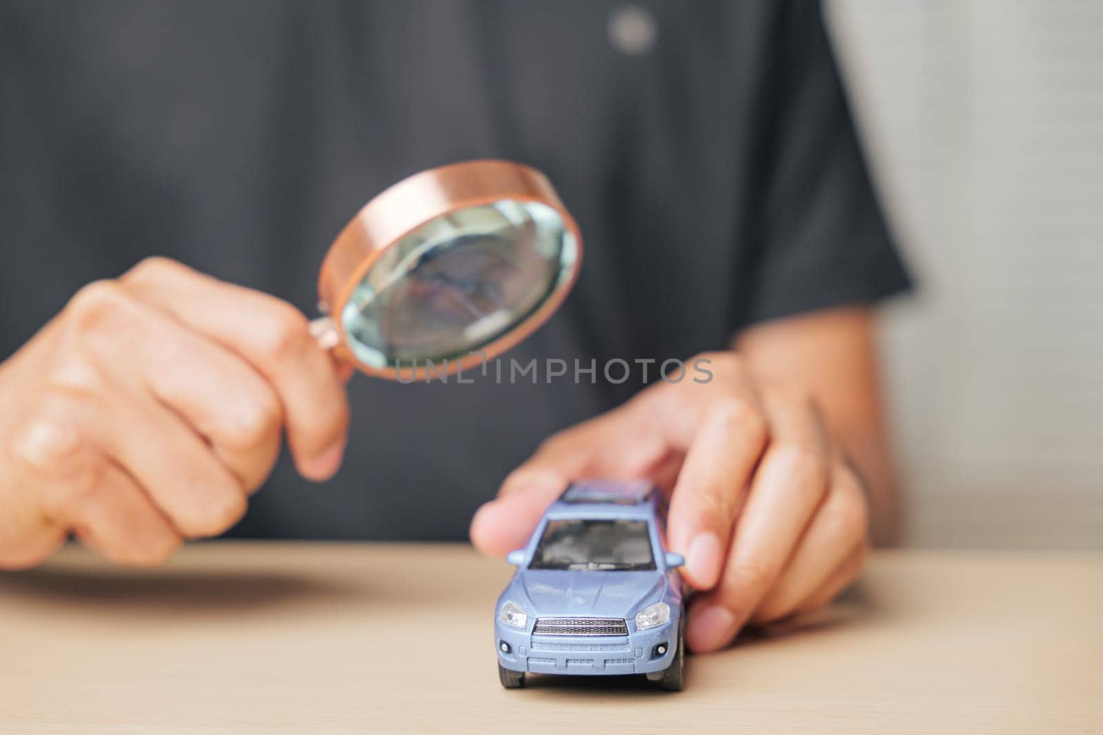 Magnifying glass focused on a car model, representing the search for automobile repair or insurance options. Concept of vehicle assessment and ensuring maintenance with careful inspection.