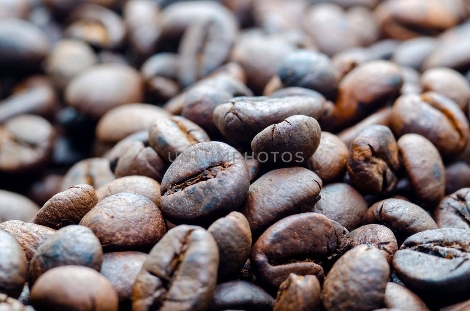 Close up view roasted coffee beans that highlights the texture and surface details of the coffee beans with customizable space for text.