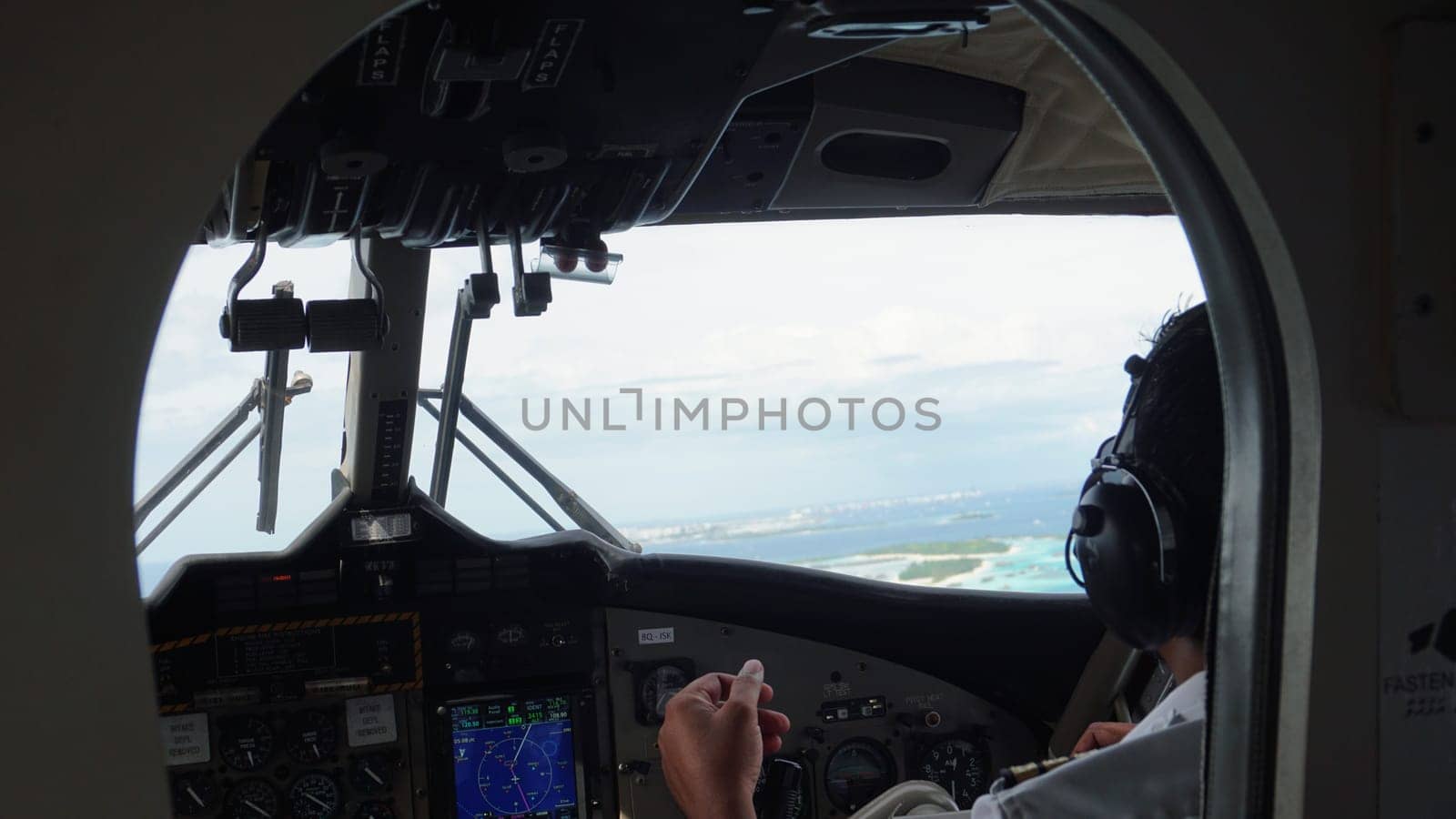 Airplane pilot navigating through the skies above a tropical maldives island, preparing for landing with a stunning turquoise lagoon and ocean in the captivating background