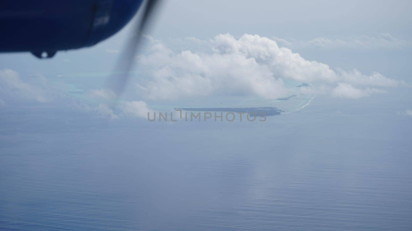 Breathtaking aerial view of a tropical island in the maldives, seen from an airplane window, showcasing the stunning beauty of the indian ocean and the lush greenery of the island