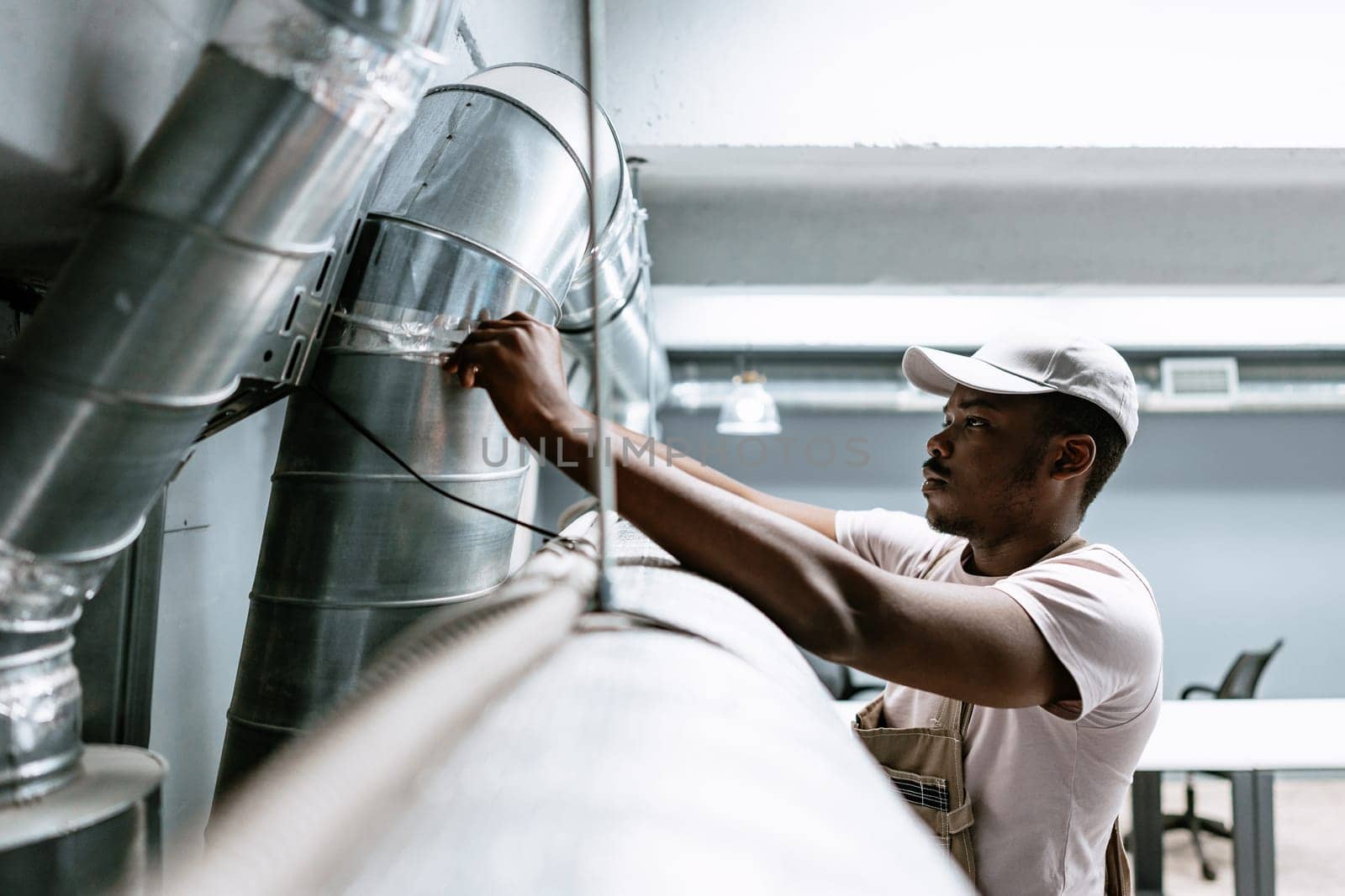 A technician is adjusting a component of the ventilation system in a contemporary office setting, focused on ensuring proper functionality and airflow.