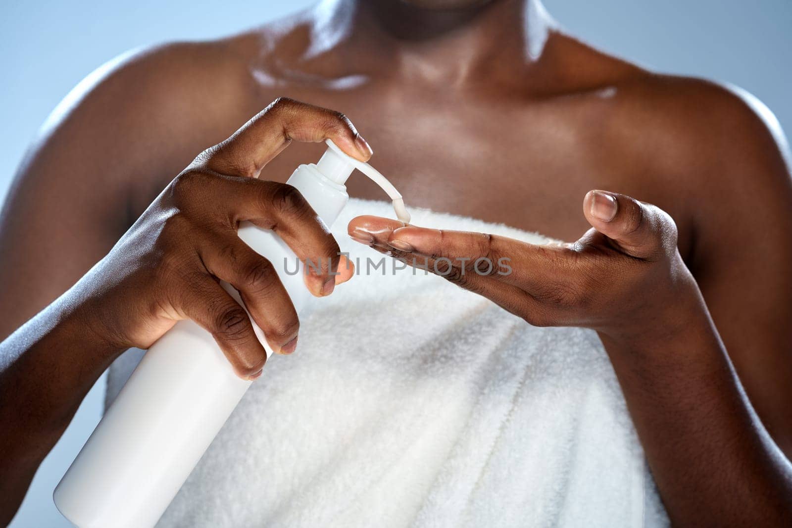 A woman is seen dispensing lotion into her hand while wrapped in a towel. She is in a softly lit bathroom reflecting a calming morning atmosphere dedicated to self-care.