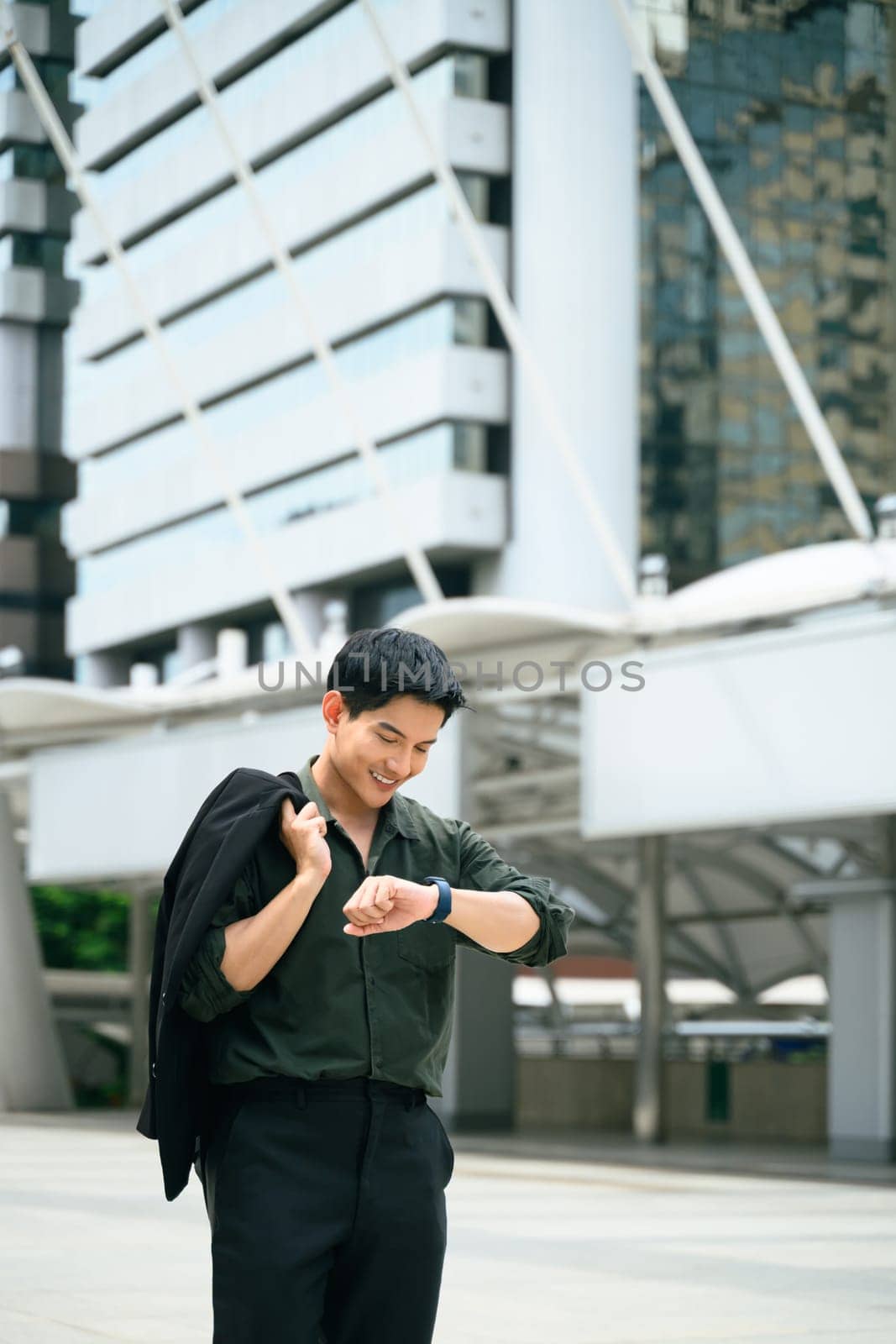Modern businessman checking the time on his smartwatch in a city business district.