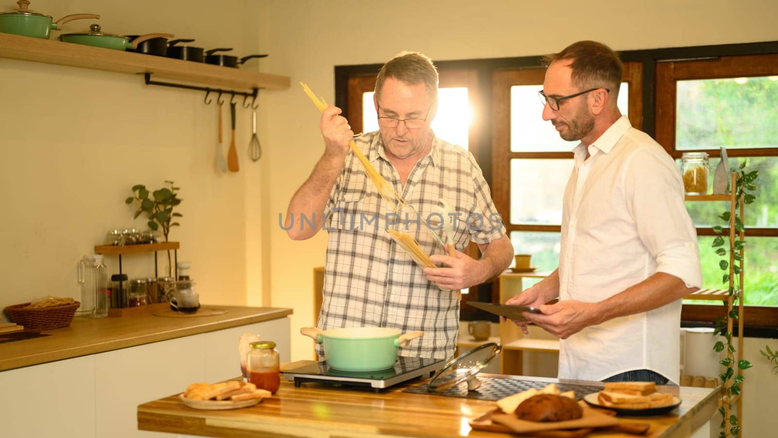 Happy father and son preparing a meal together and conversation in a kitchen. Fathers day concept.