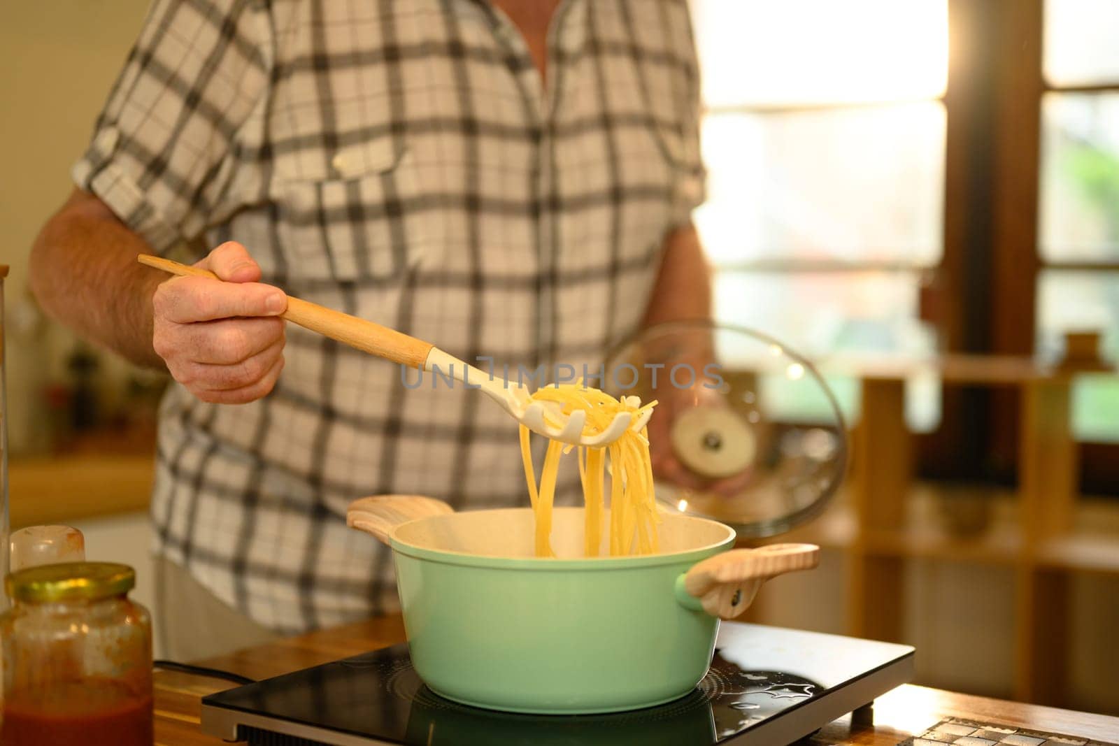 Close up of mature man preparing spaghetti in a cozy kitchen.