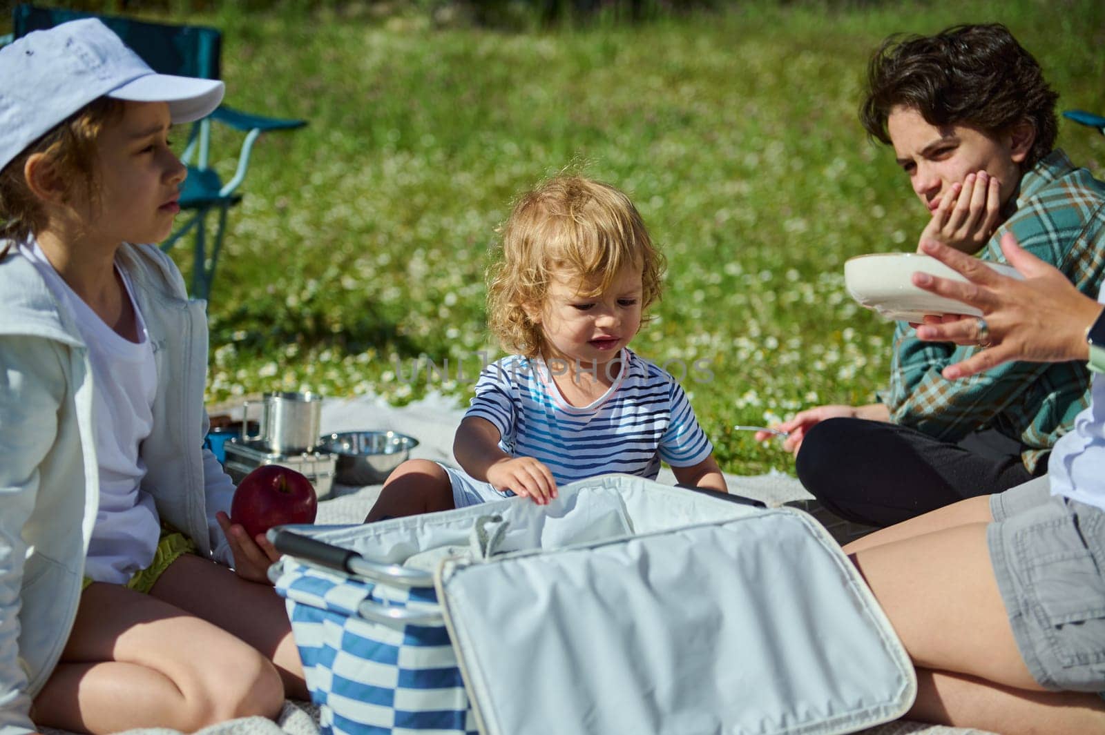 A cheerful scene of a family enjoying an outdoor picnic in a natural setting. Parents and children share quality time during a sunny day in the mountains.