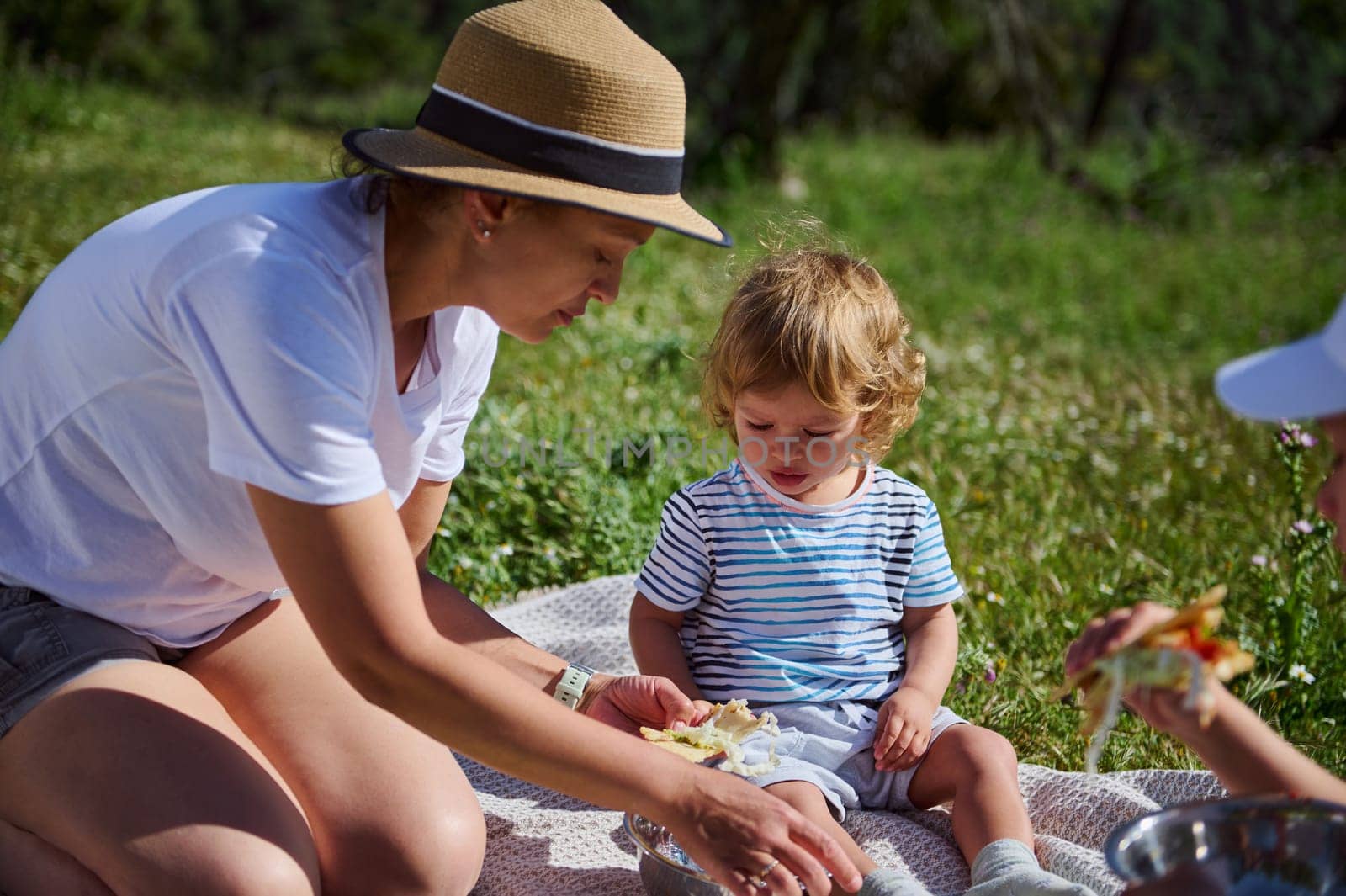 A charming family moment as a mother spends joyful time with her child during a picnic in the scenic mountains, surrounded by natural beauty under warm summer sunshine.