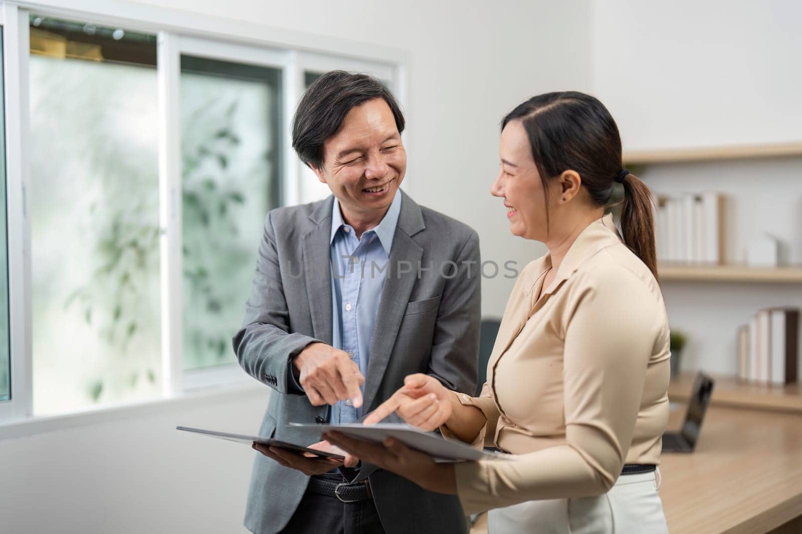 A businessman and businesswoman share insights while reviewing documents, emphasizing teamwork and collaboration in a professional setting.
