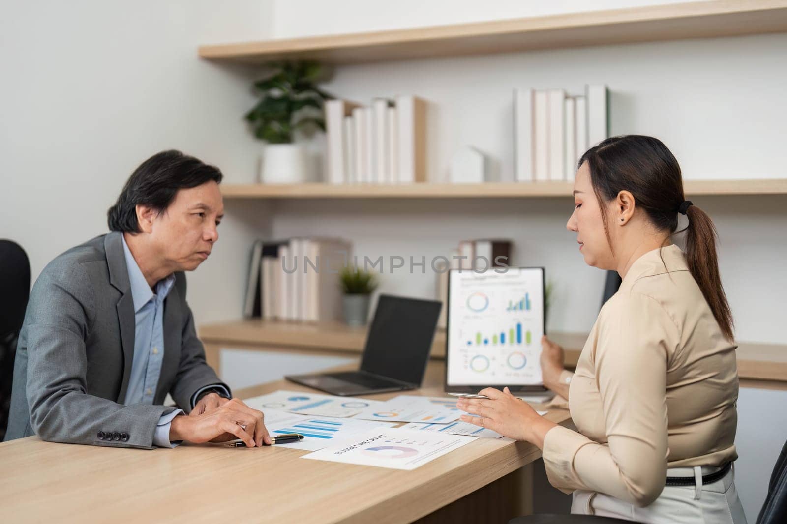 Two colleagues engage in a business meeting, analyzing financial reports and discussing strategies in a contemporary office.