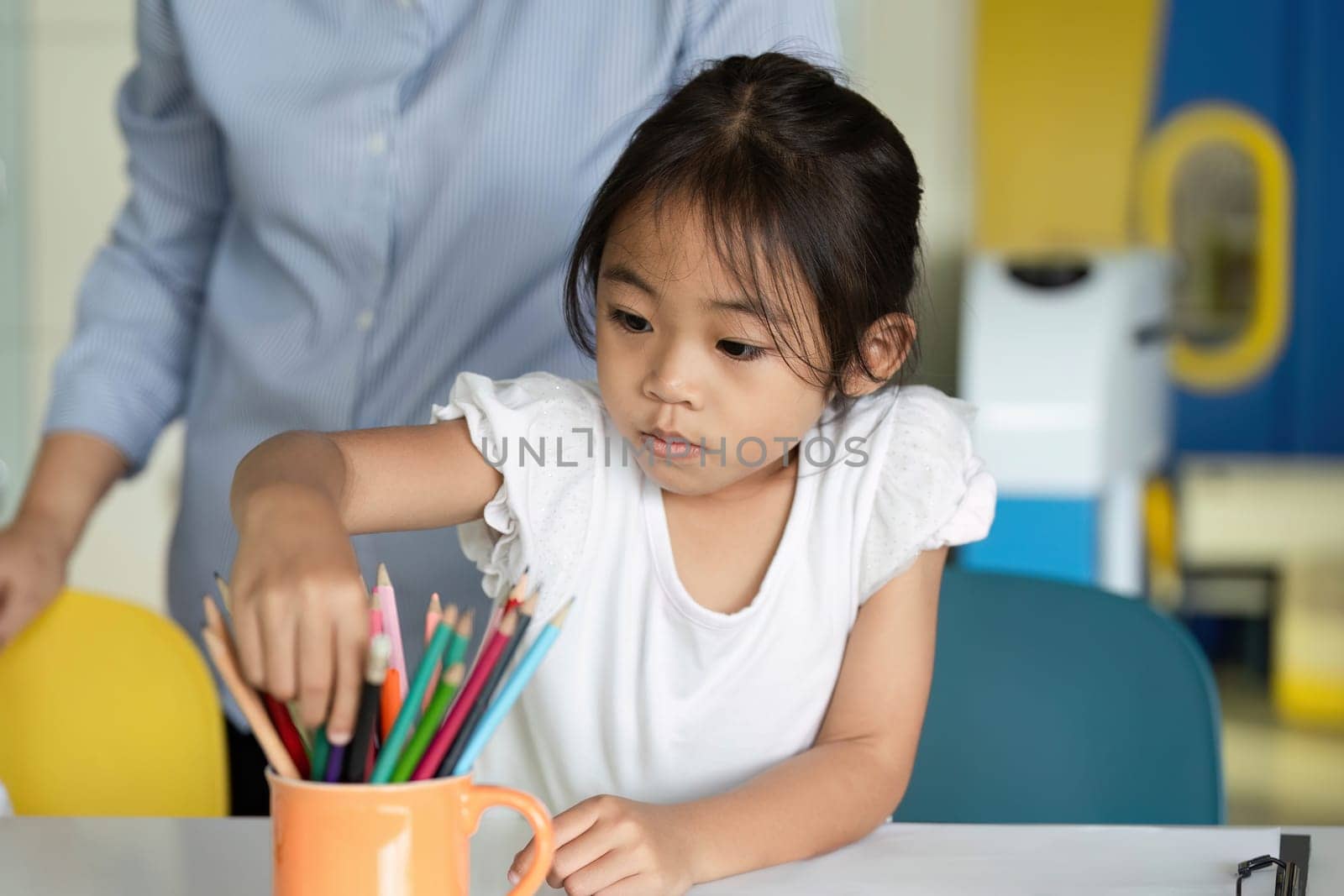 A young girl carefully picks out pencils, demonstrating focus and creativity during an art activity in a classroom.