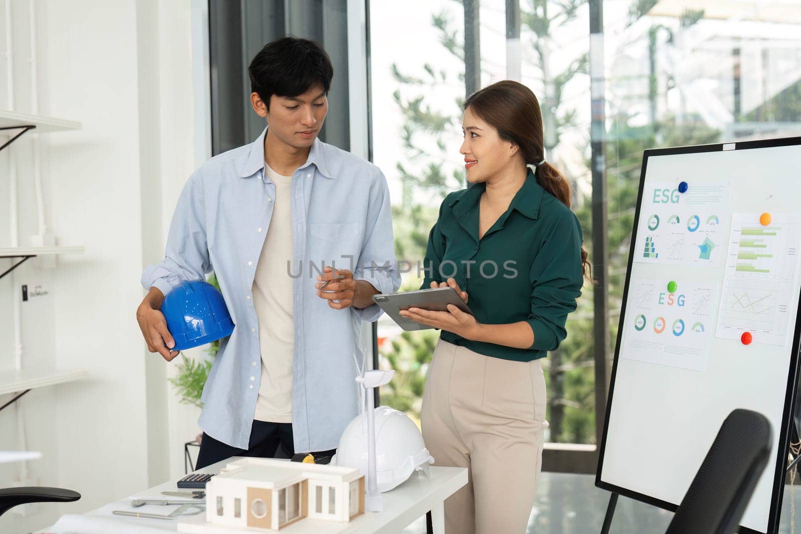 A man and woman discuss sustainable energy solutions, showcasing ESG values in a contemporary office environment.