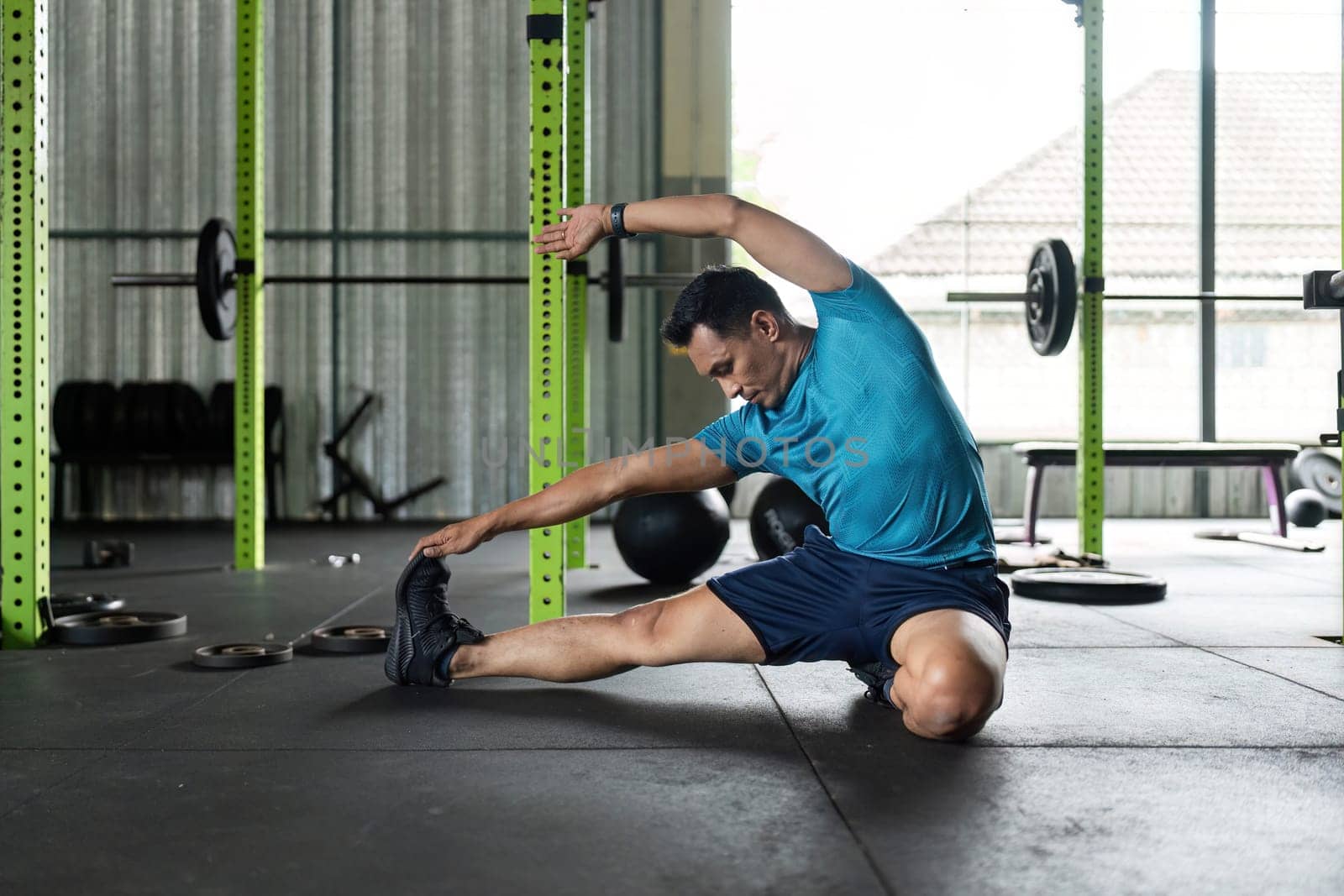 A fit man performs a side stretch in a gym, focusing on flexibility and wellness. Ideal for health and fitness themes.