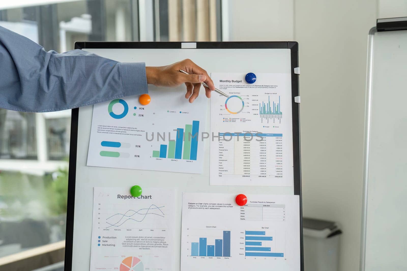 A businessman highlights key metrics on a presentation board, emphasizing financial planning and strategy in a corporate setting.
