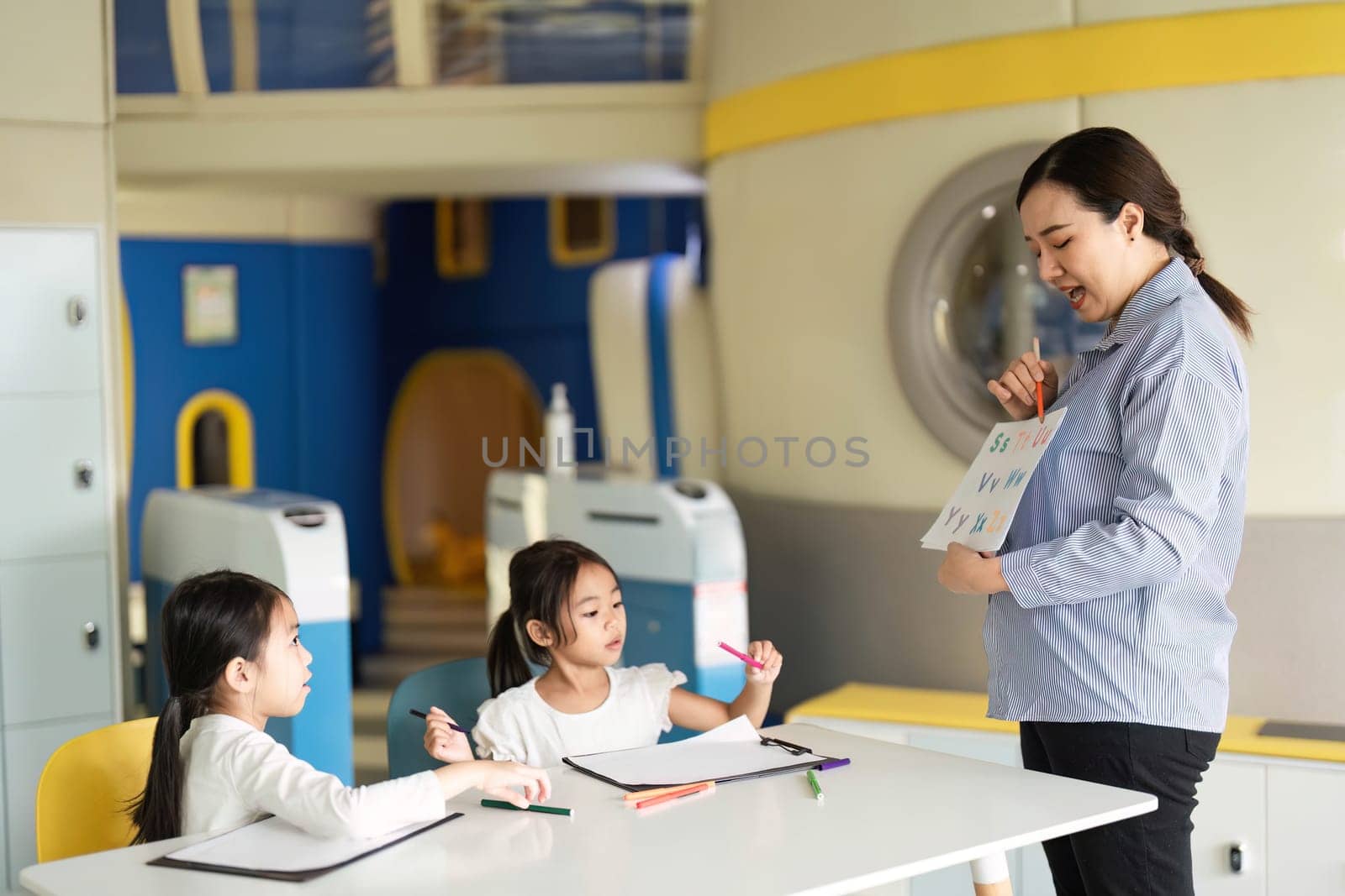 A teacher showcases the alphabet to curious students in a vibrant classroom, fostering a love for learning through interaction.