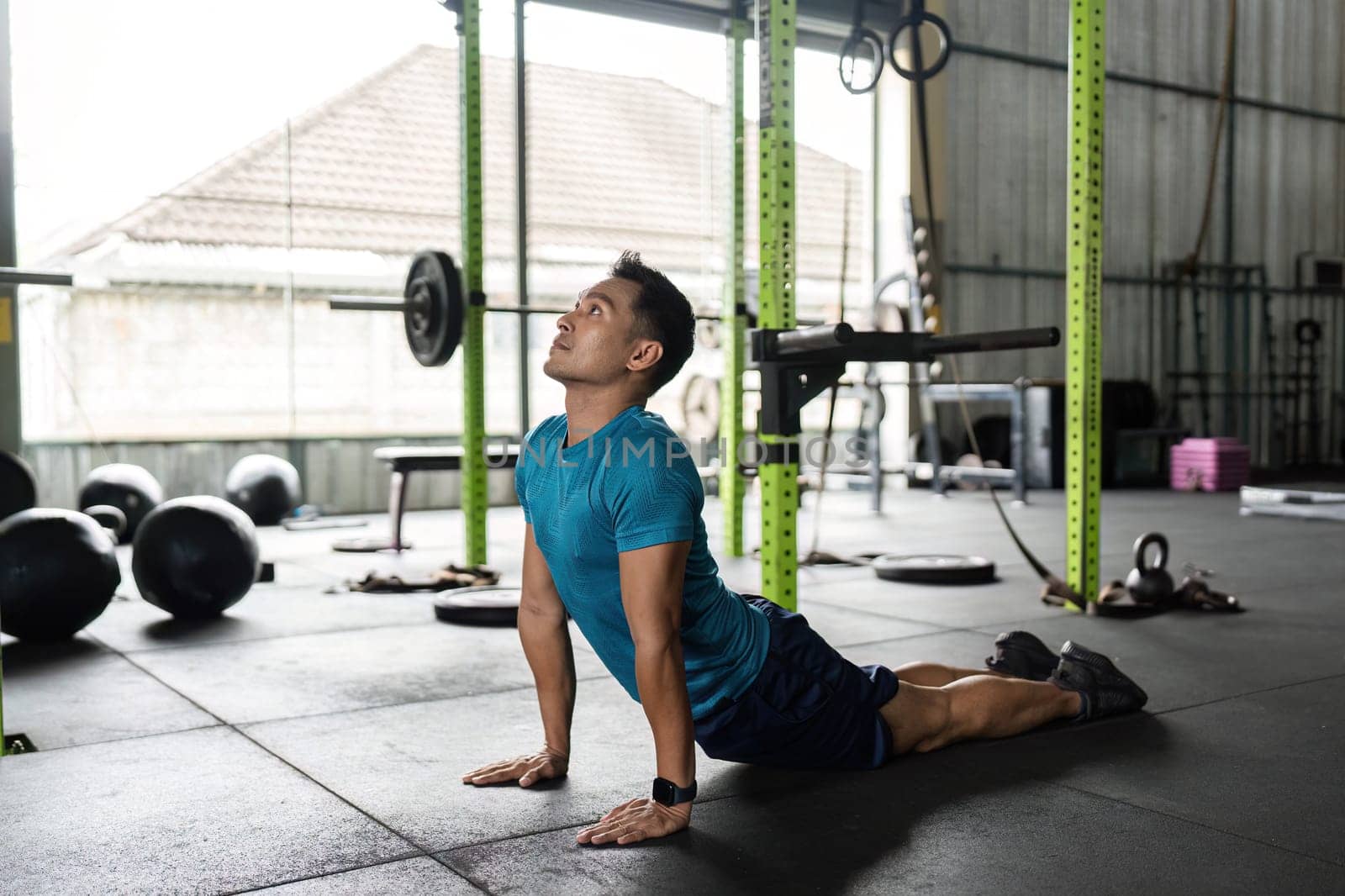 A fit man engaging in yoga stretches in a modern gym, promoting flexibility and wellness. Ideal for fitness and health themes.