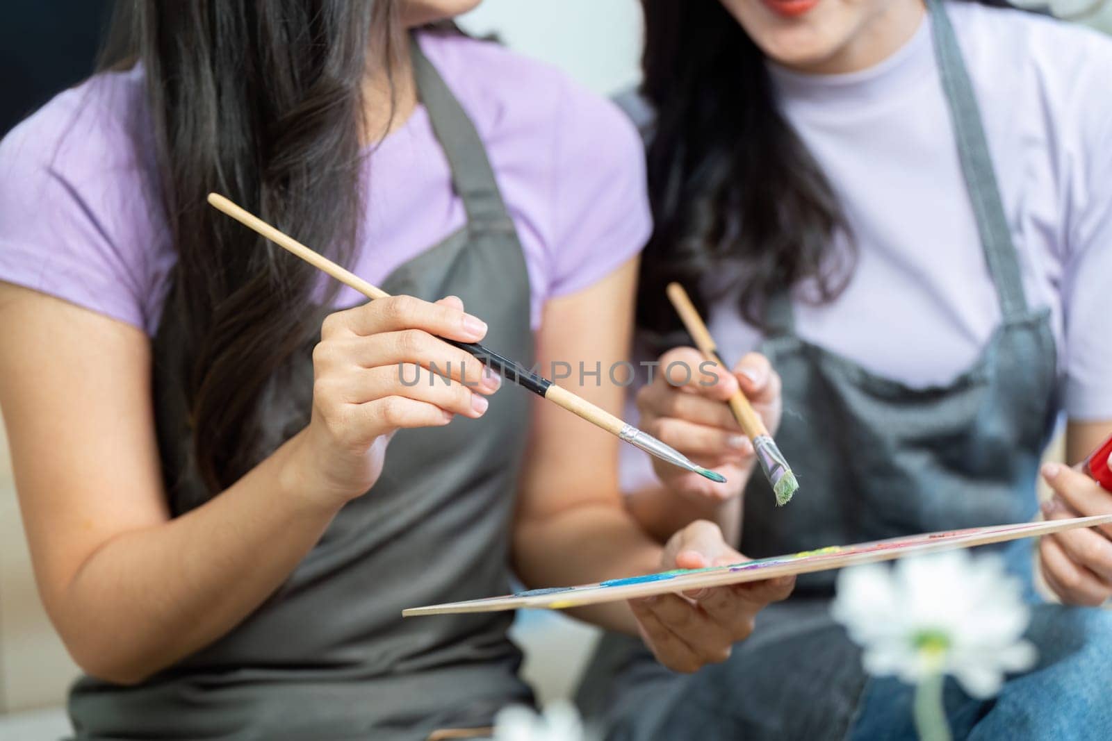 Two women engaged in a joyful painting session, showcasing their creativity and love in a cozy indoor space.