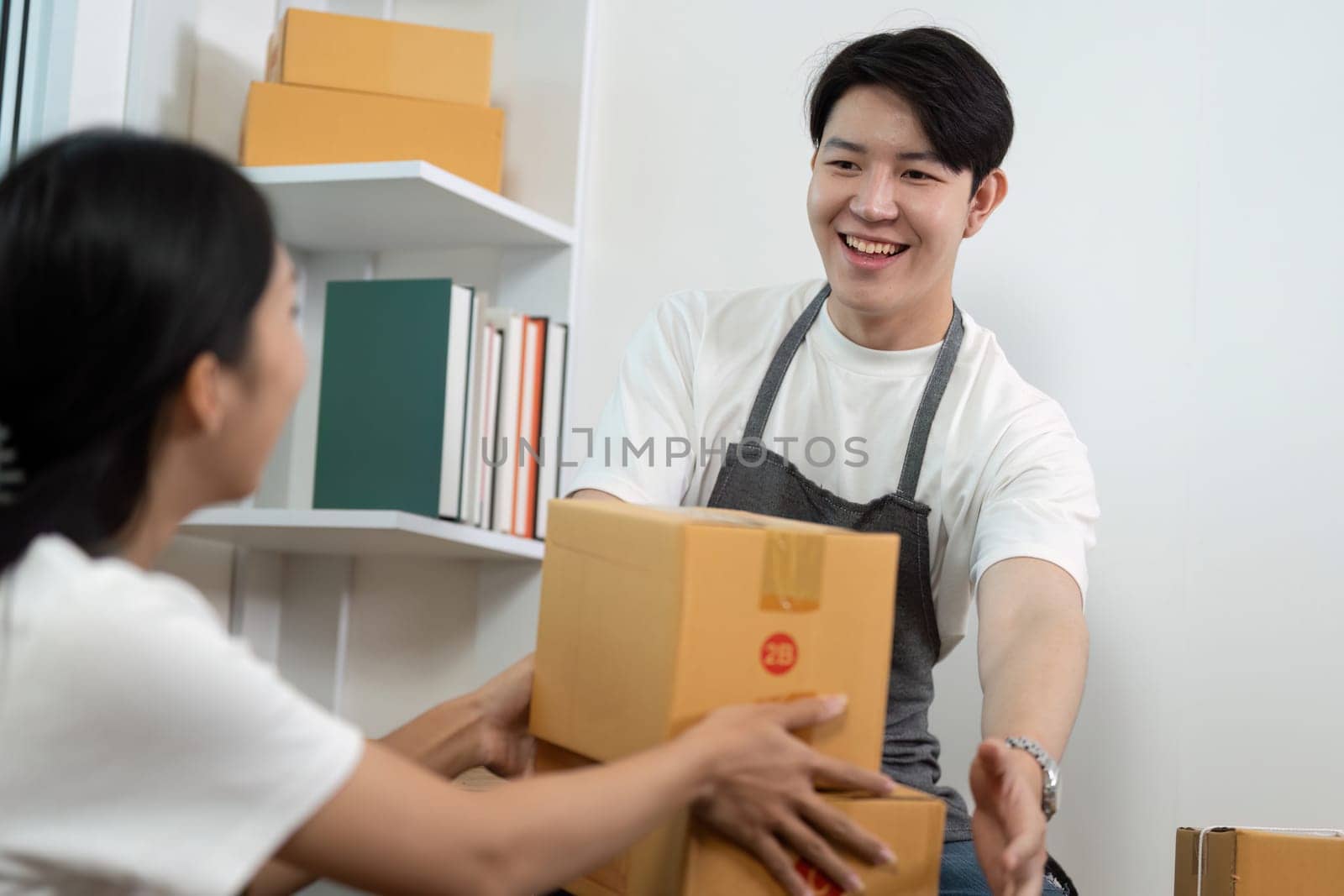 A couple engages in a productive exchange while handling packages in a contemporary office setting, showcasing teamwork and communication.