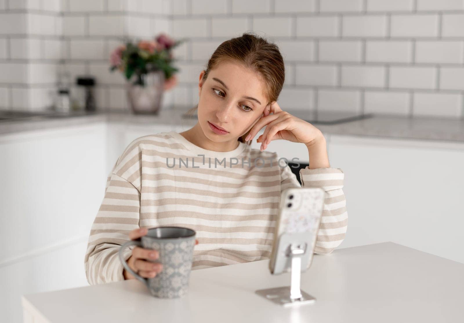 Sad Teen Girl At Home Looking At Something On Smartphone