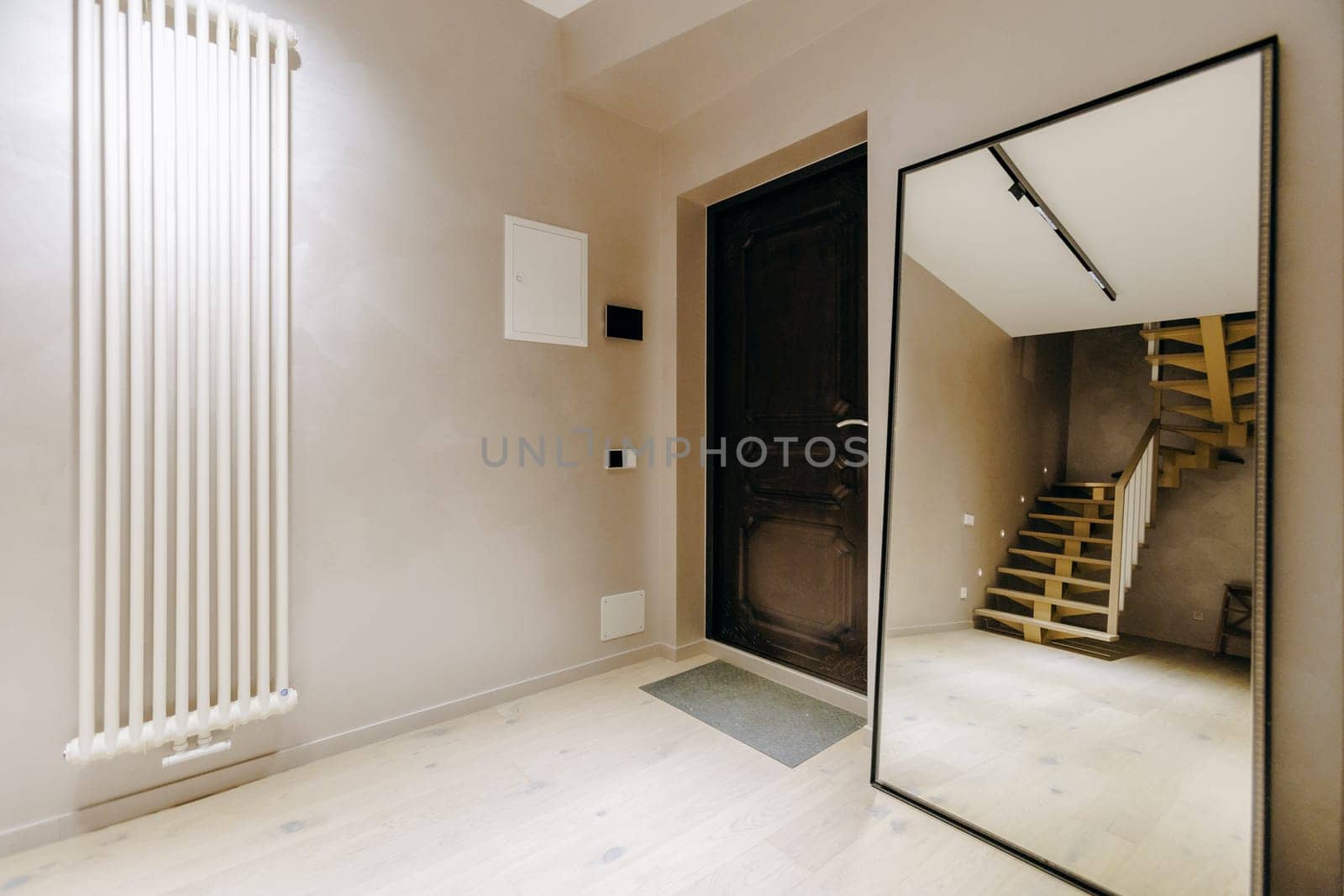 A hallway featuring a large mirror along with a radiator installed, creating a cohesive and functional space within the home