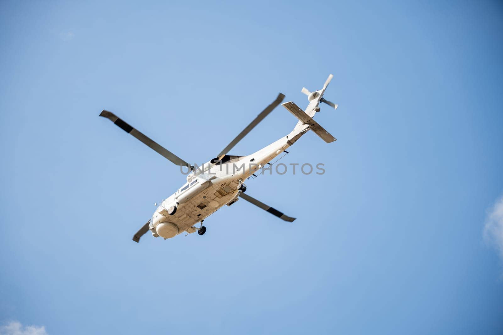 Helicopter in flight against blue sky demonstrating modern rescue and transport technology. New engine hovering capabilities. Pilot maneuvers small aircraft's speed and angles.