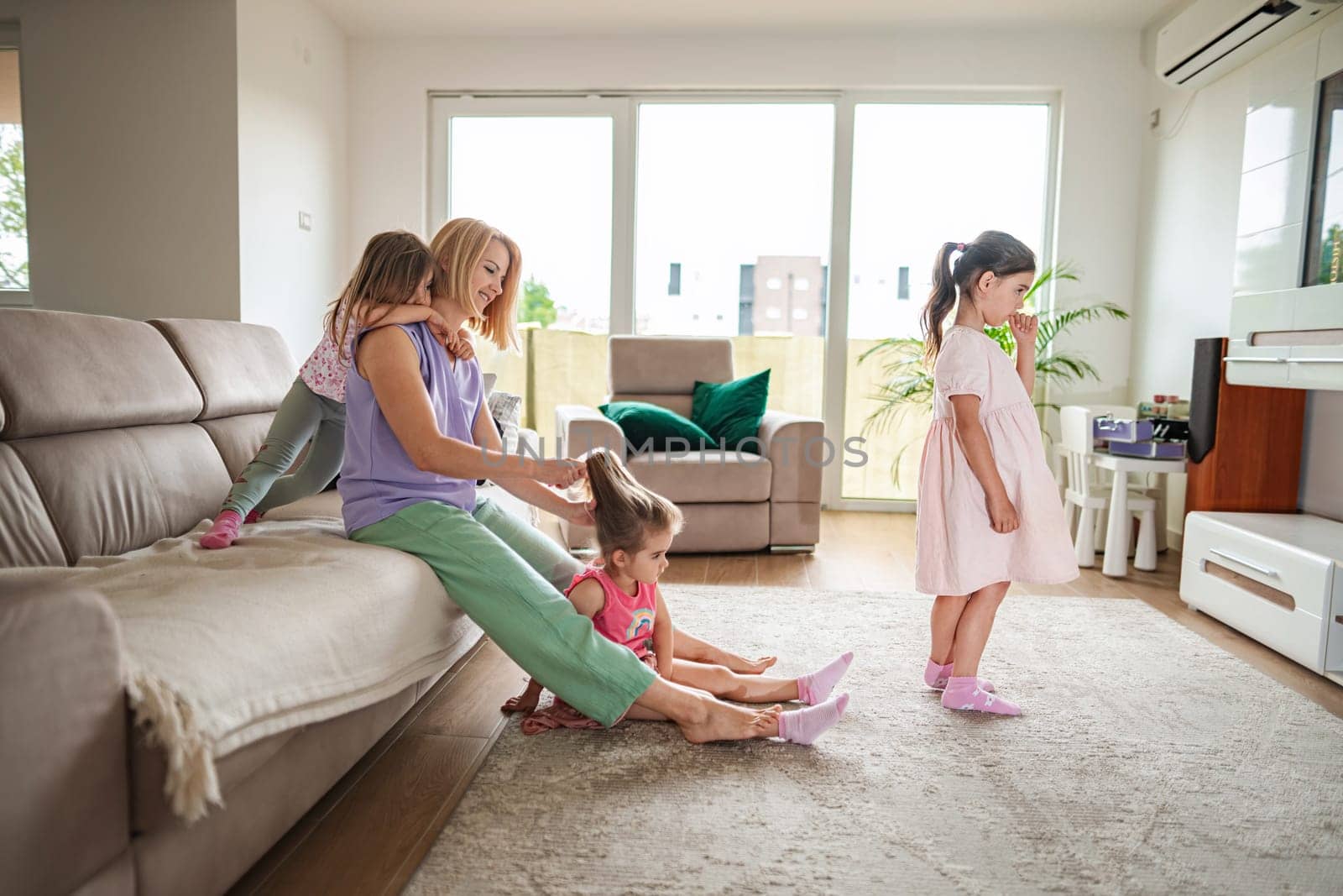 A mother delights in grooming her daughters in sunny comfort.