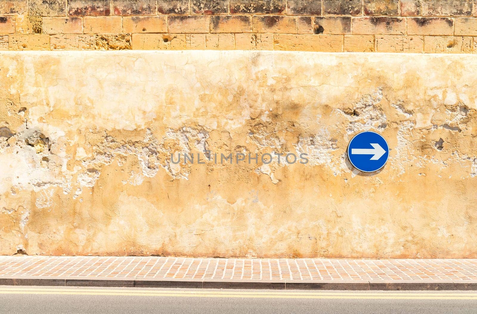 Cracked wall with a safety sign on it, proceed right only.