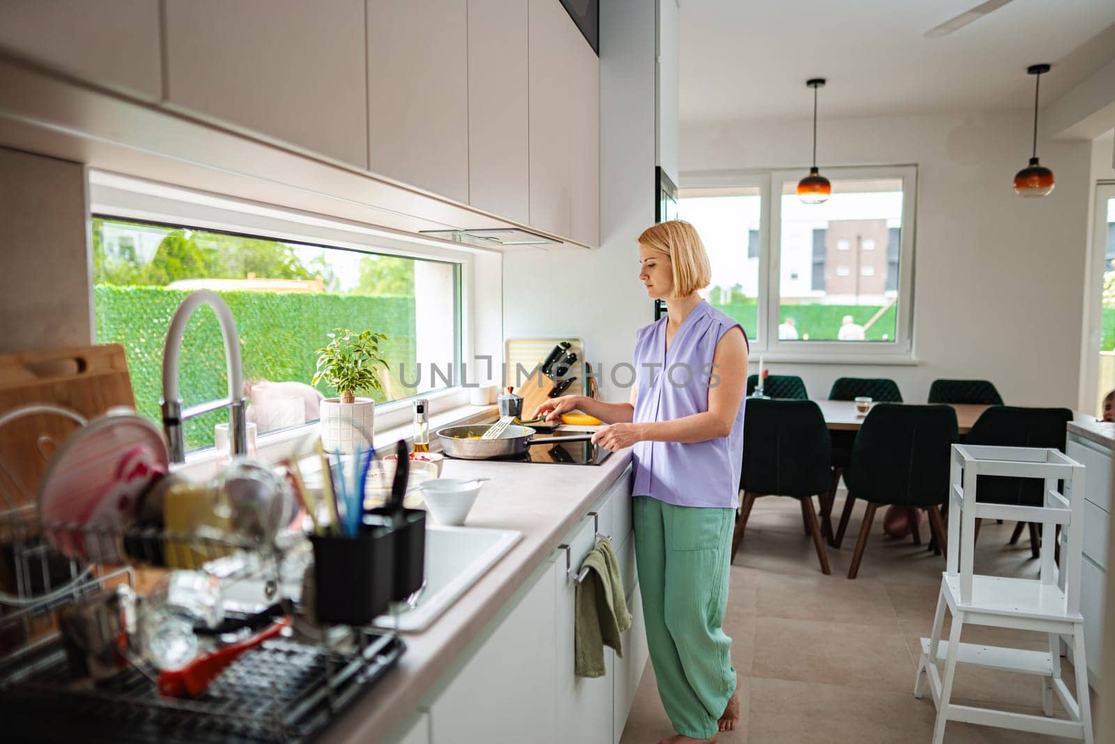 A woman prepares a meal while enjoying natural light.