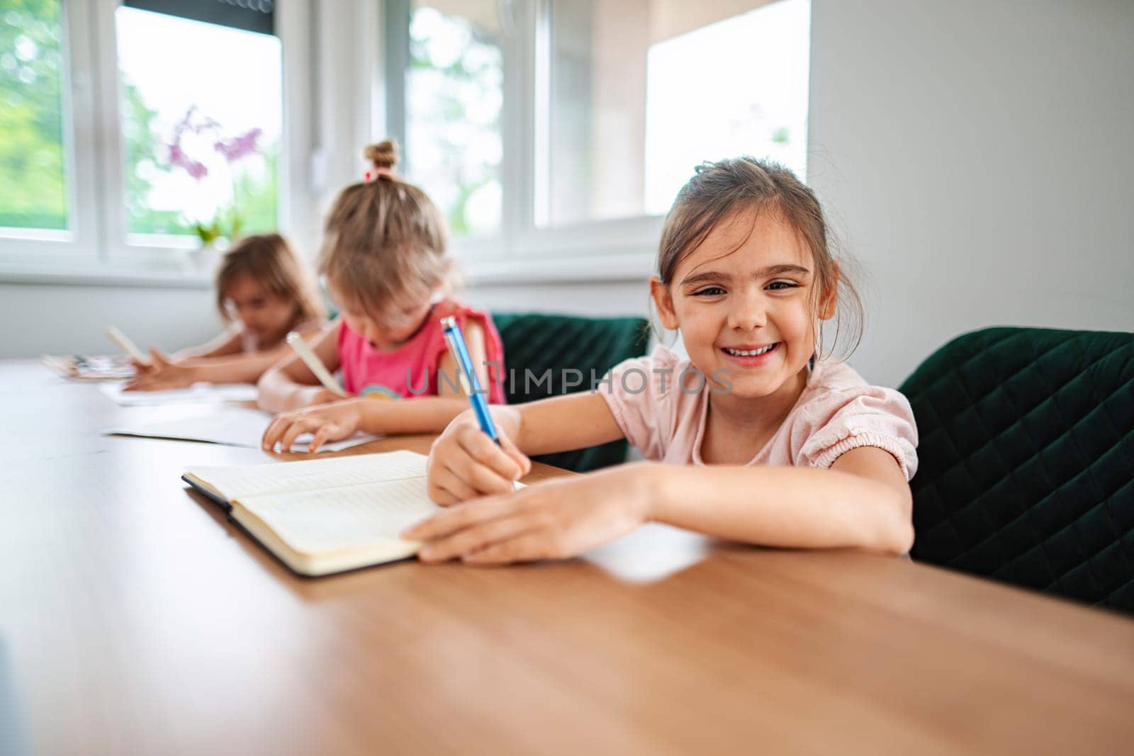 Children happily writing and learning at a study table.