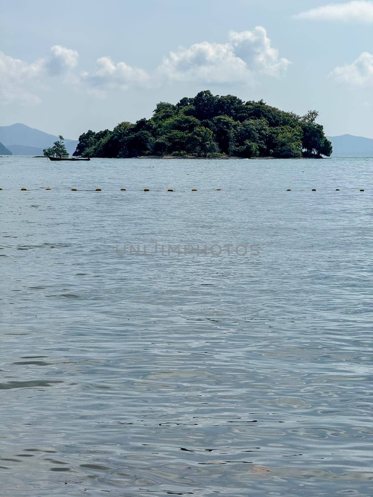 Multiple boats sailing along a sunlit blue tropical Thai coastline, wanderlust scenery featuring sailboats moving across a blue ocean. Bright summer sky and palm trees along the shoreline.