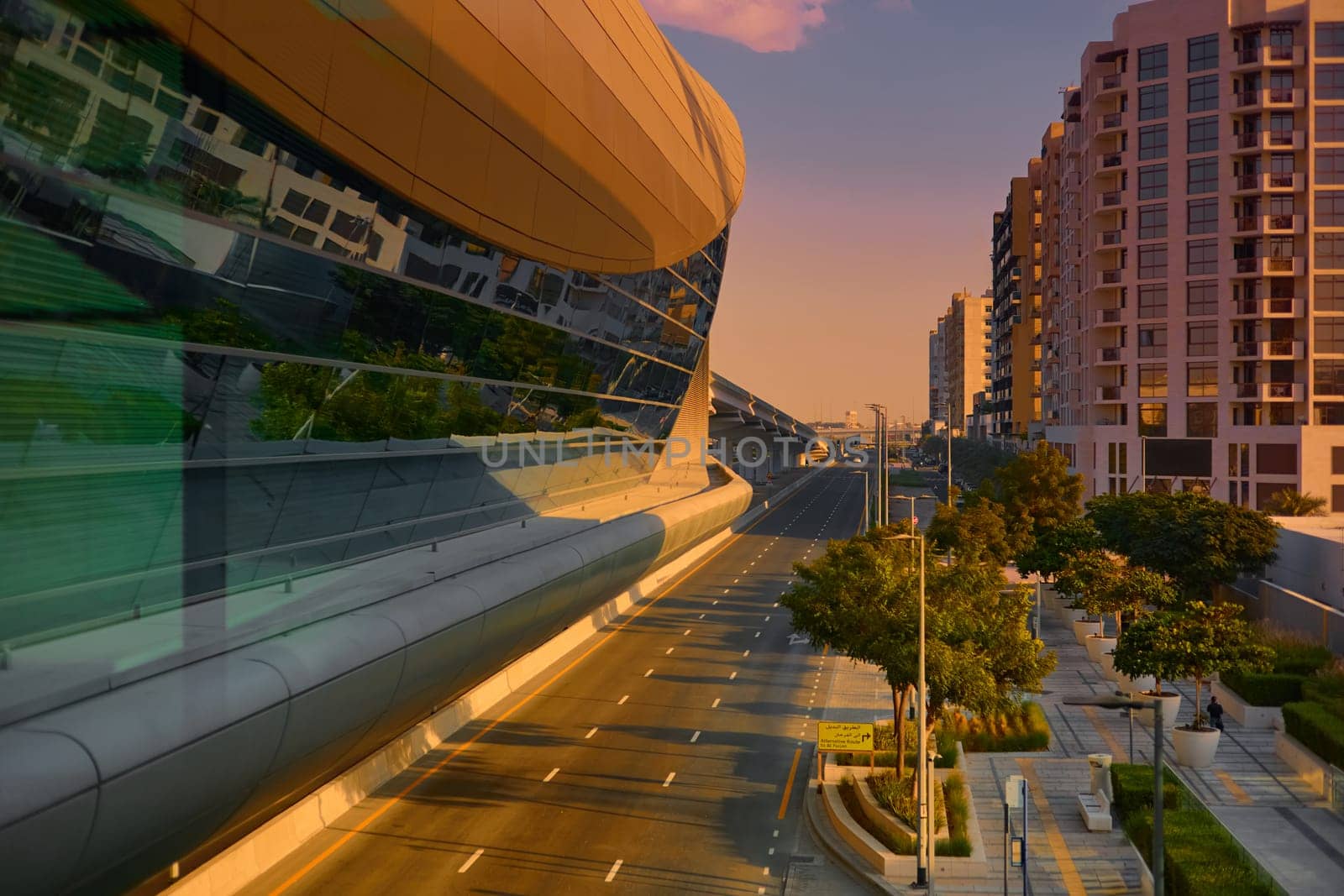 UAE, Dubai, 11 December 2024: Facade of subway over highway, architecture of the city at sunset, building with glass facades. High quality photo