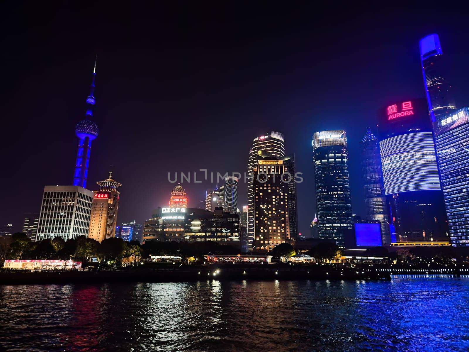 Shanghai, China - 1 April 2025: Colorful night skyline of Pudong with illuminated skyscrapers and reflections on the Huangpu River, viewed from the Bund.