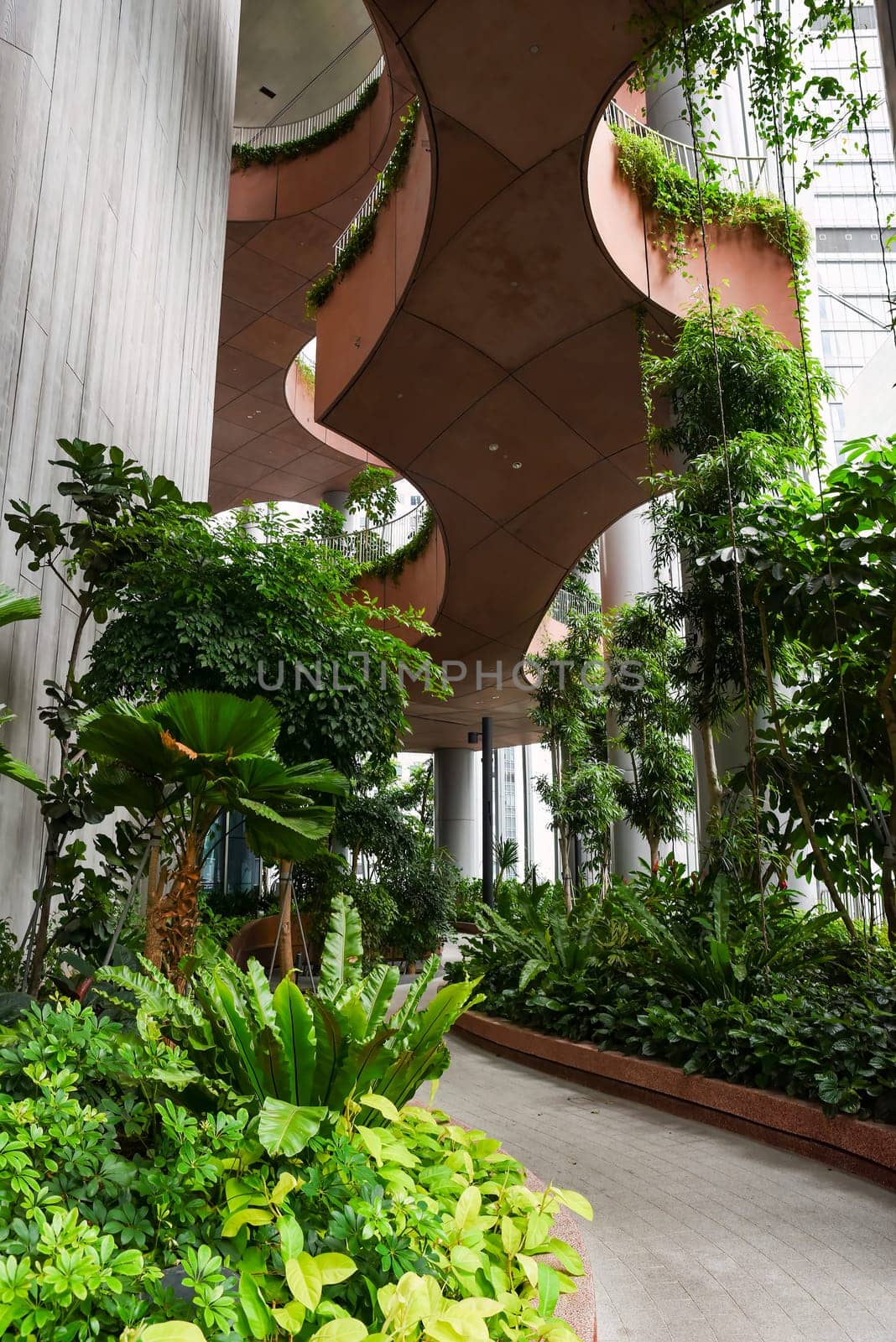 Singapore, Singapore - 4 April 2025: Indoor sky garden with tropical plants and curved architecture inside Capita Spring building in central business district.