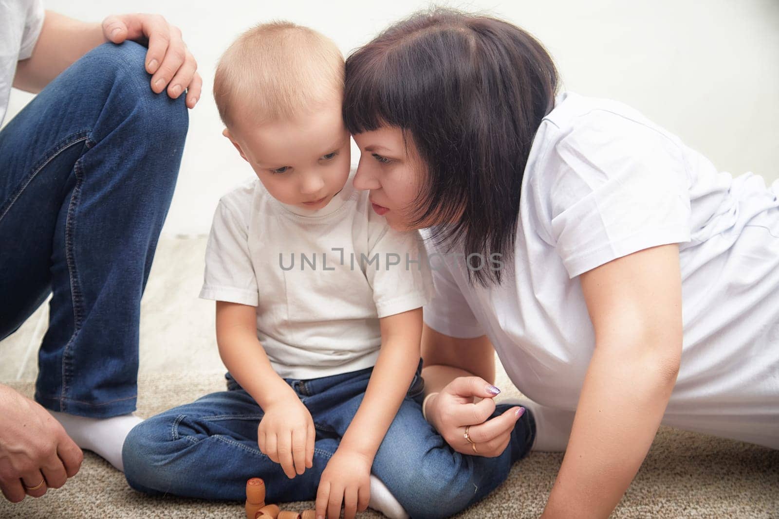 A young boy listens intently as his mother speaks to him softly while they sit close together on a carpet.