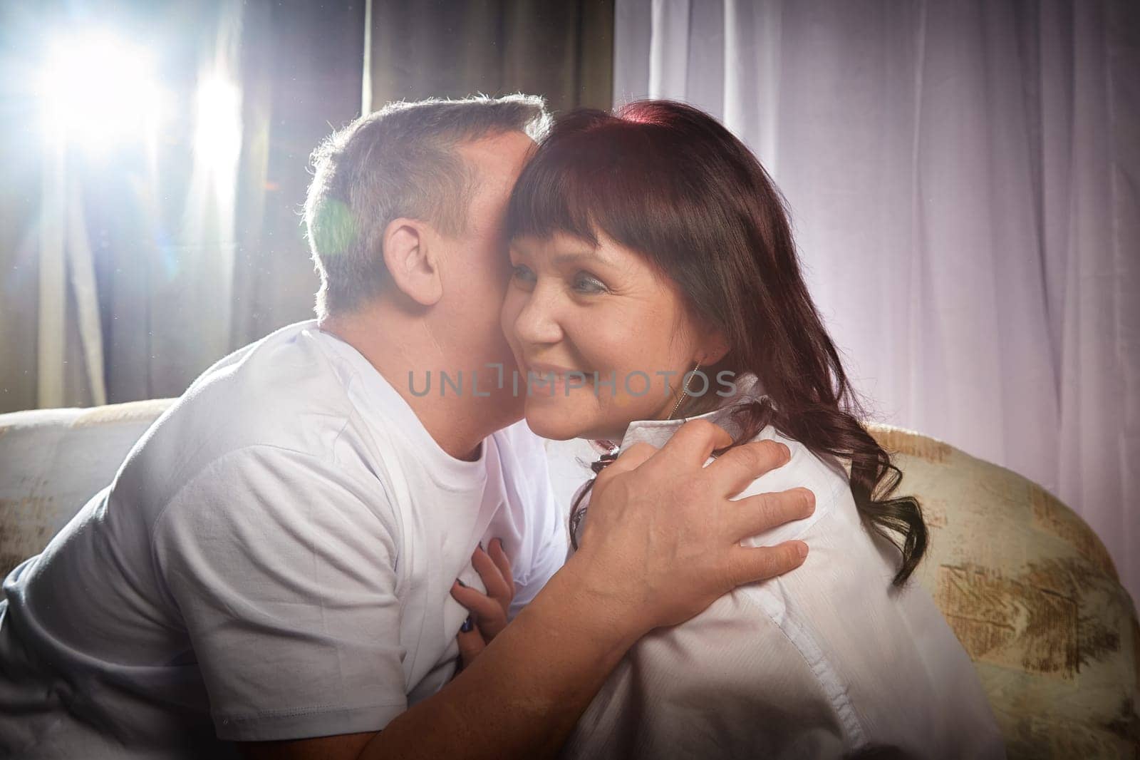 A loving couple enjoys a close embrace, capturing their affection in an indoor setting full of warmth and intimacy.