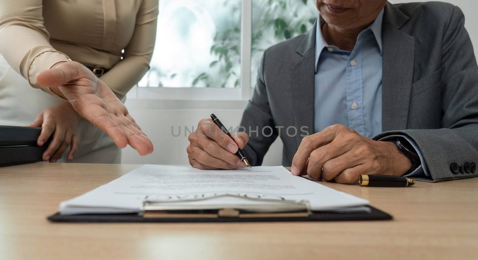 A businessman reviews and signs important documents, showcasing professionalism and commitment in a corporate setting.