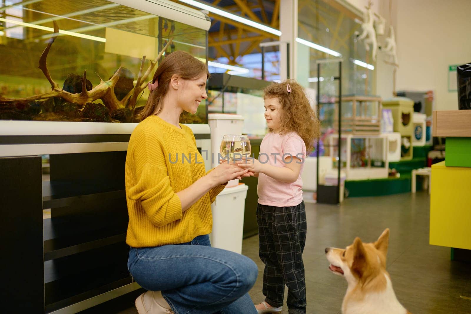 Portrait of happy mother and little daughter bought fish at pet shop