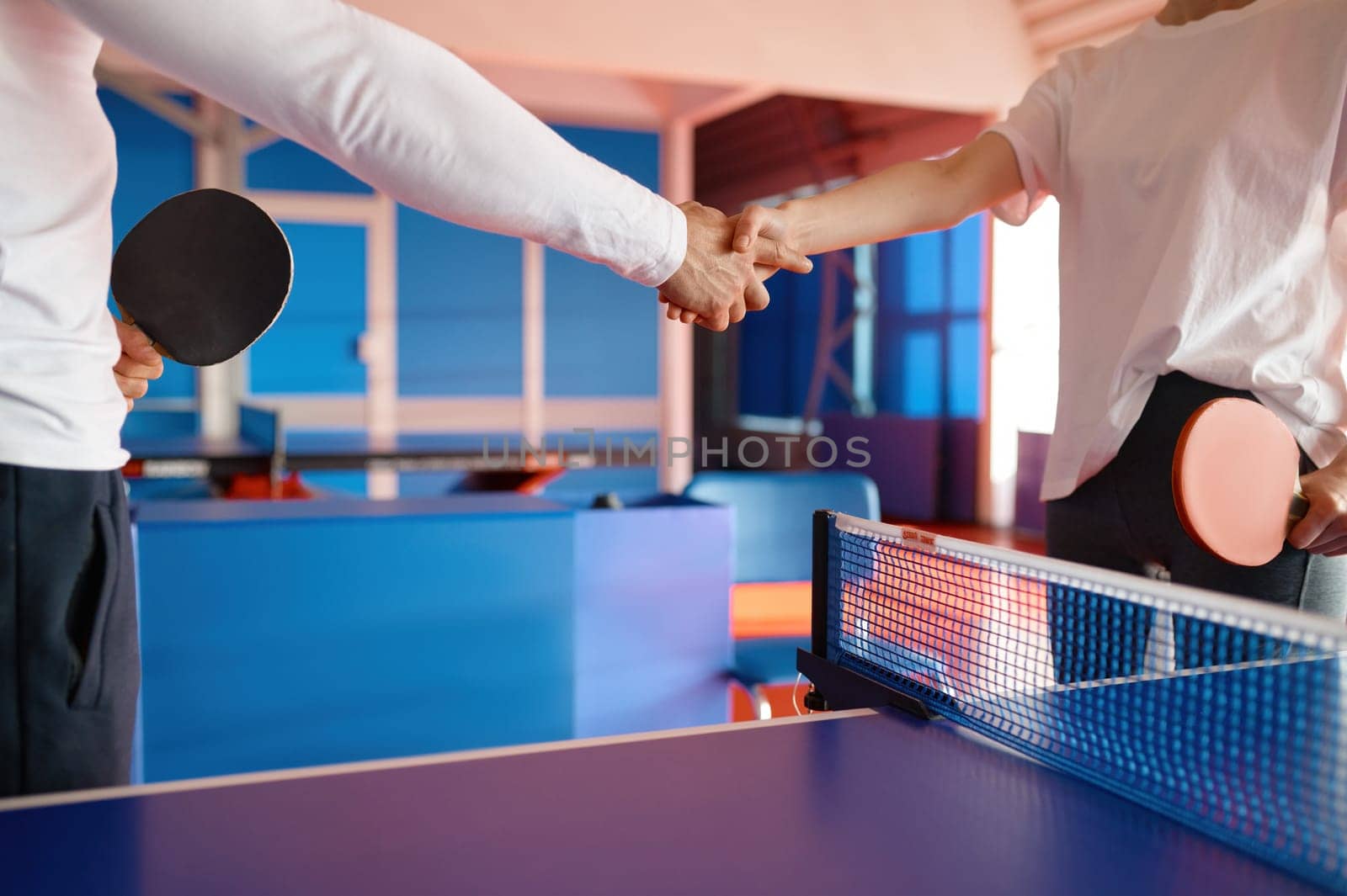 Two table tennis player shaking hands greeting each other with successful friendly match cropped shot