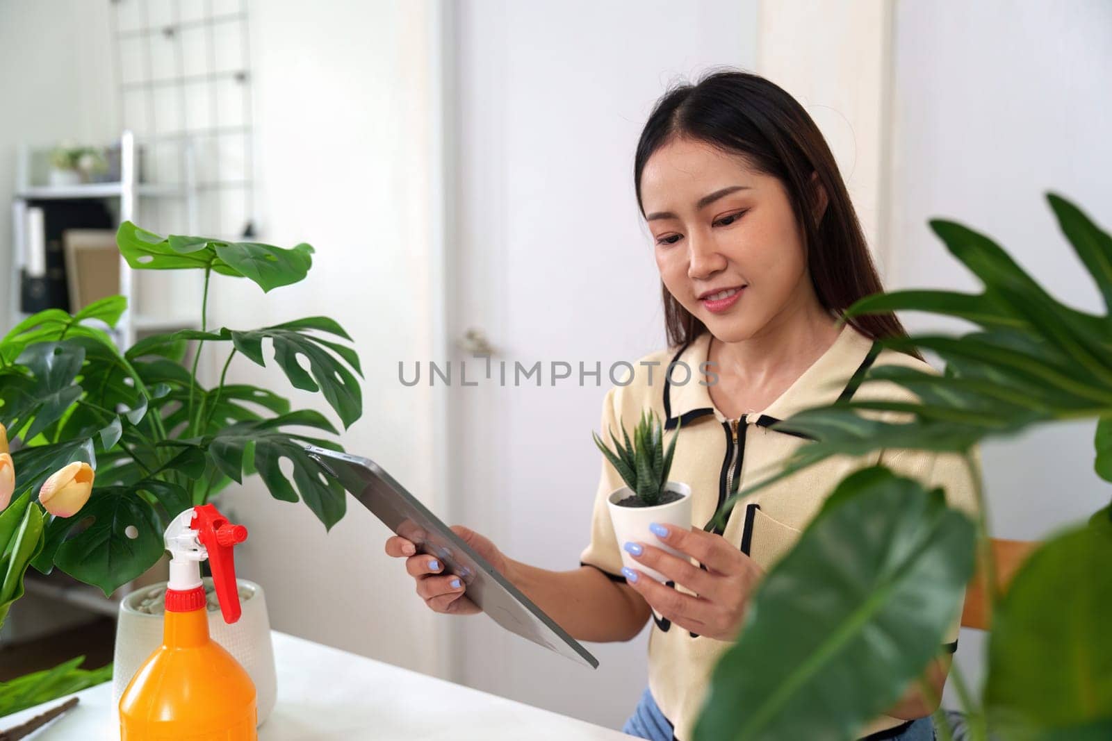 A plant enthusiast examines a small succulent while documenting her indoor gardening progress on a tablet, reflecting on sustainable hobbies.