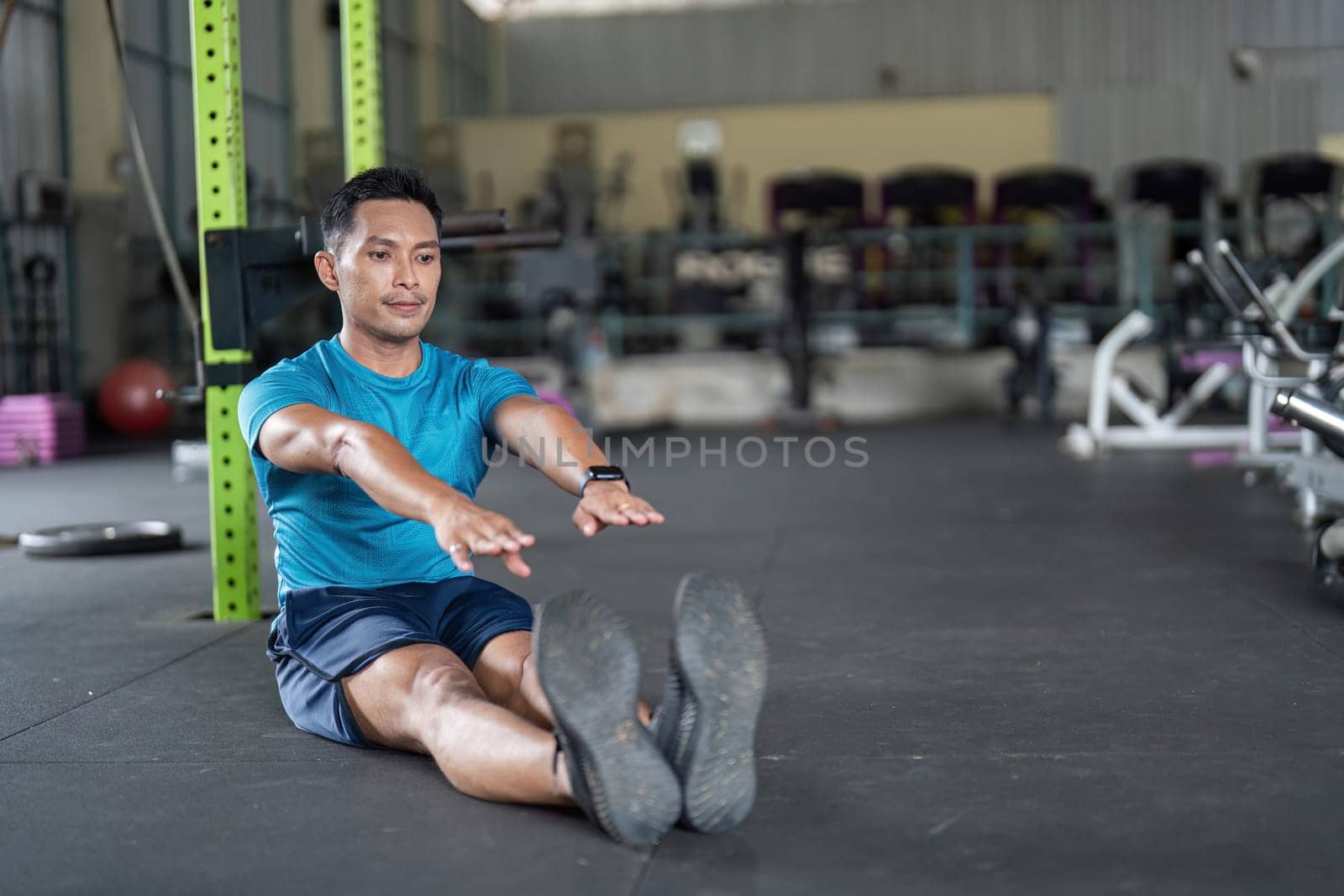 A young man focuses on his fitness routine, performing a forward stretch to enhance flexibility and overall health.