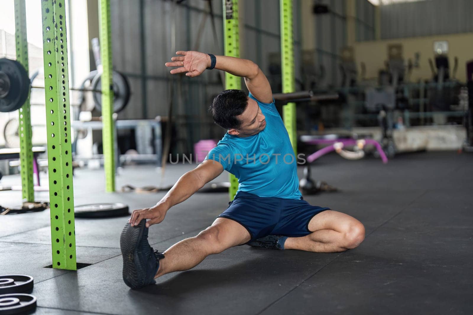 A young man engages in a side stretch exercise, enhancing flexibility and promoting a healthy lifestyle in a fitness center.