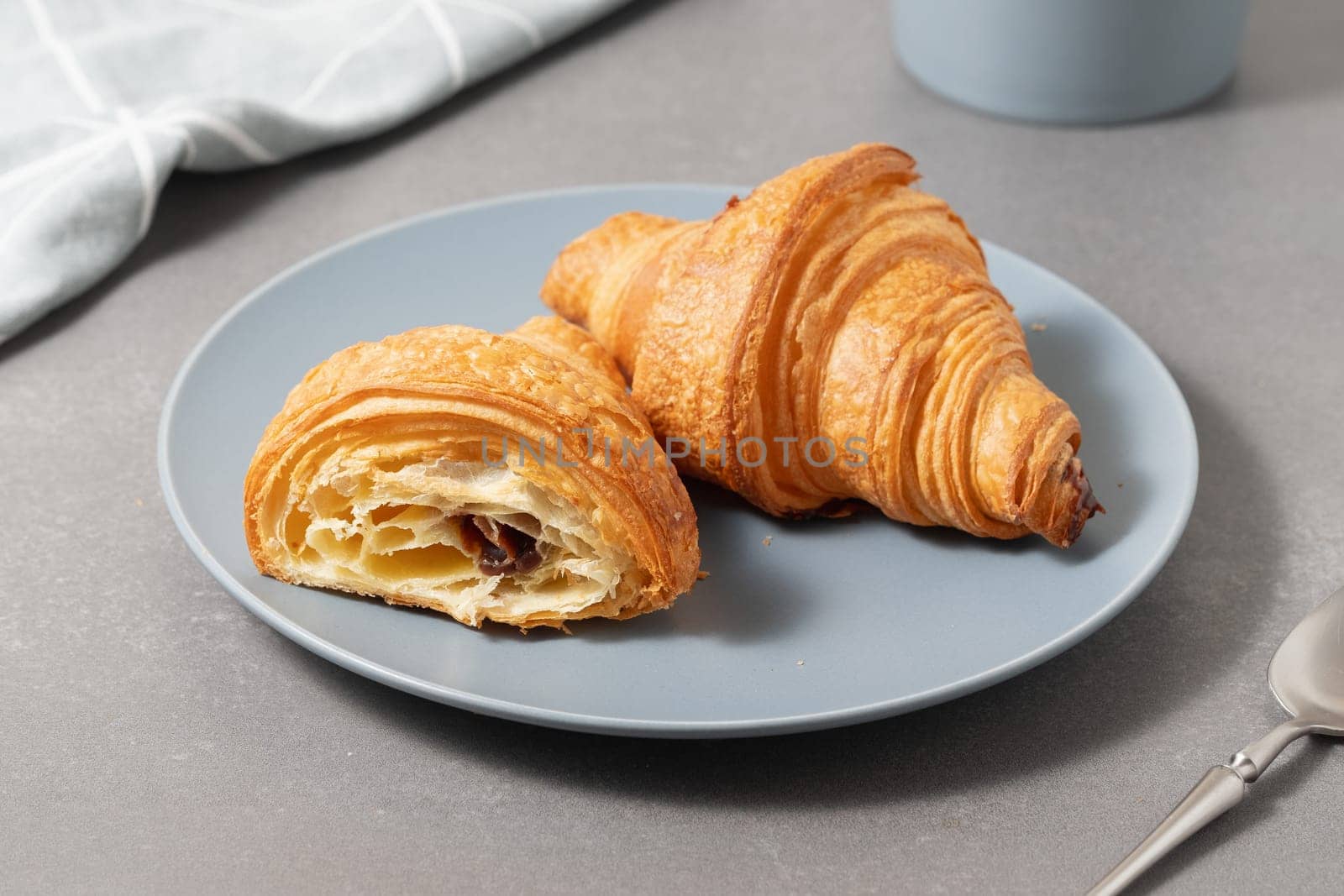 Freshly baked golden croissants on a blue plate ready for breakfast in a cozy kitchen setting.