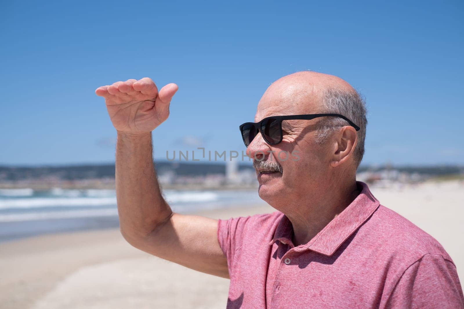 Elderly Man with Mustache and Sunglasses Looking into the Distance over the Ocean.Travel and Tourism in Retirement