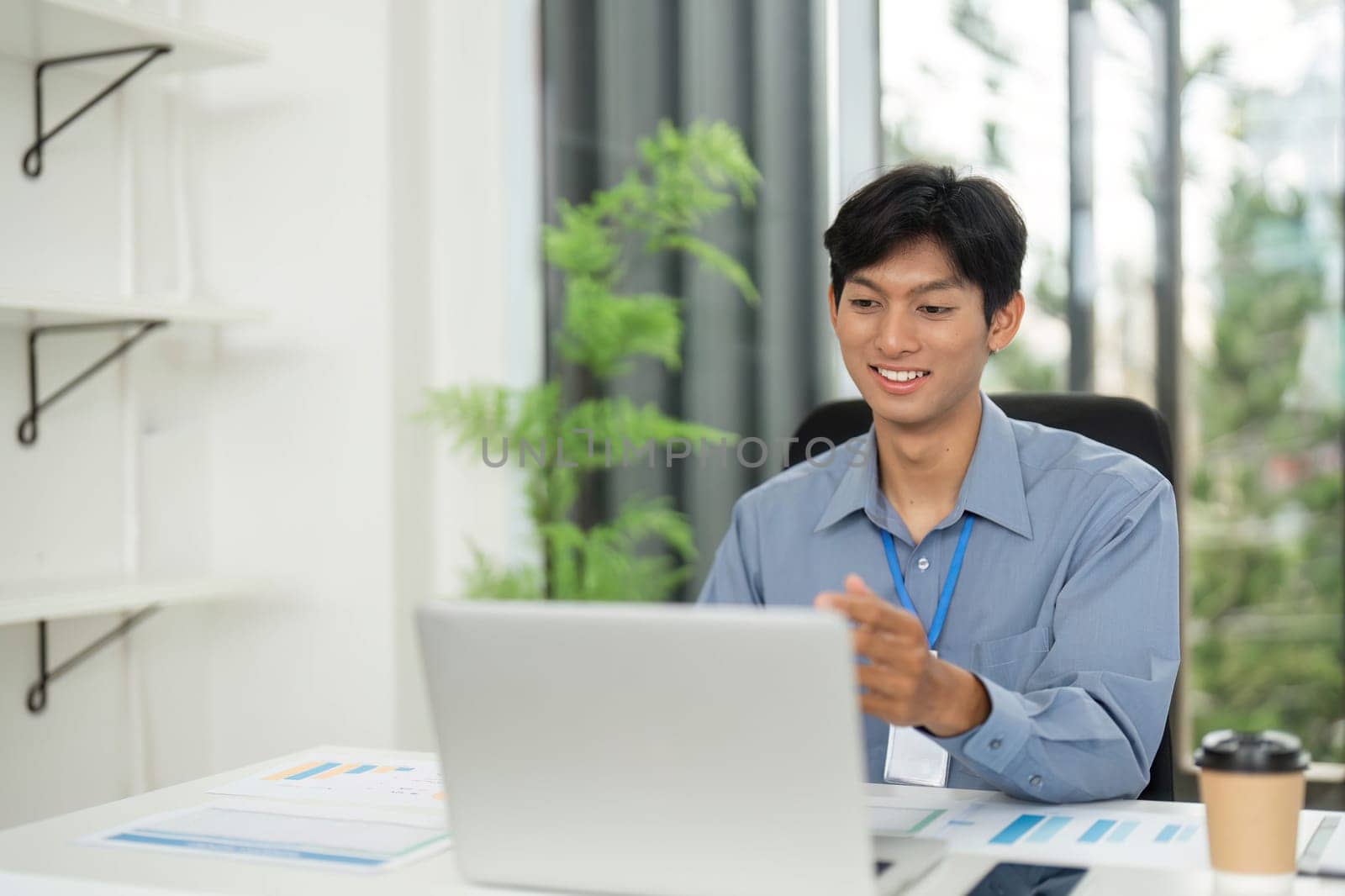 A cheerful young professional enjoys his work at a laptop, embodying a positive and productive workplace atmosphere.
