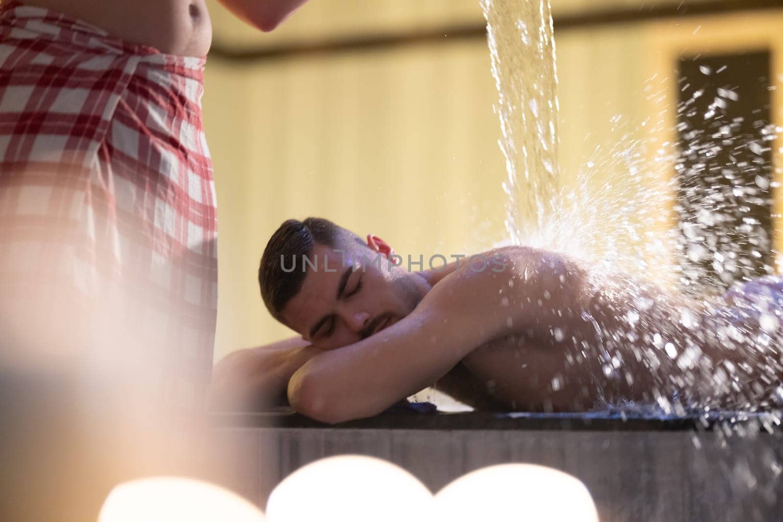 Water Treatment in Turkish Hammam.Man receiving water therapy inside a traditional Turkish hammam with ornate details.