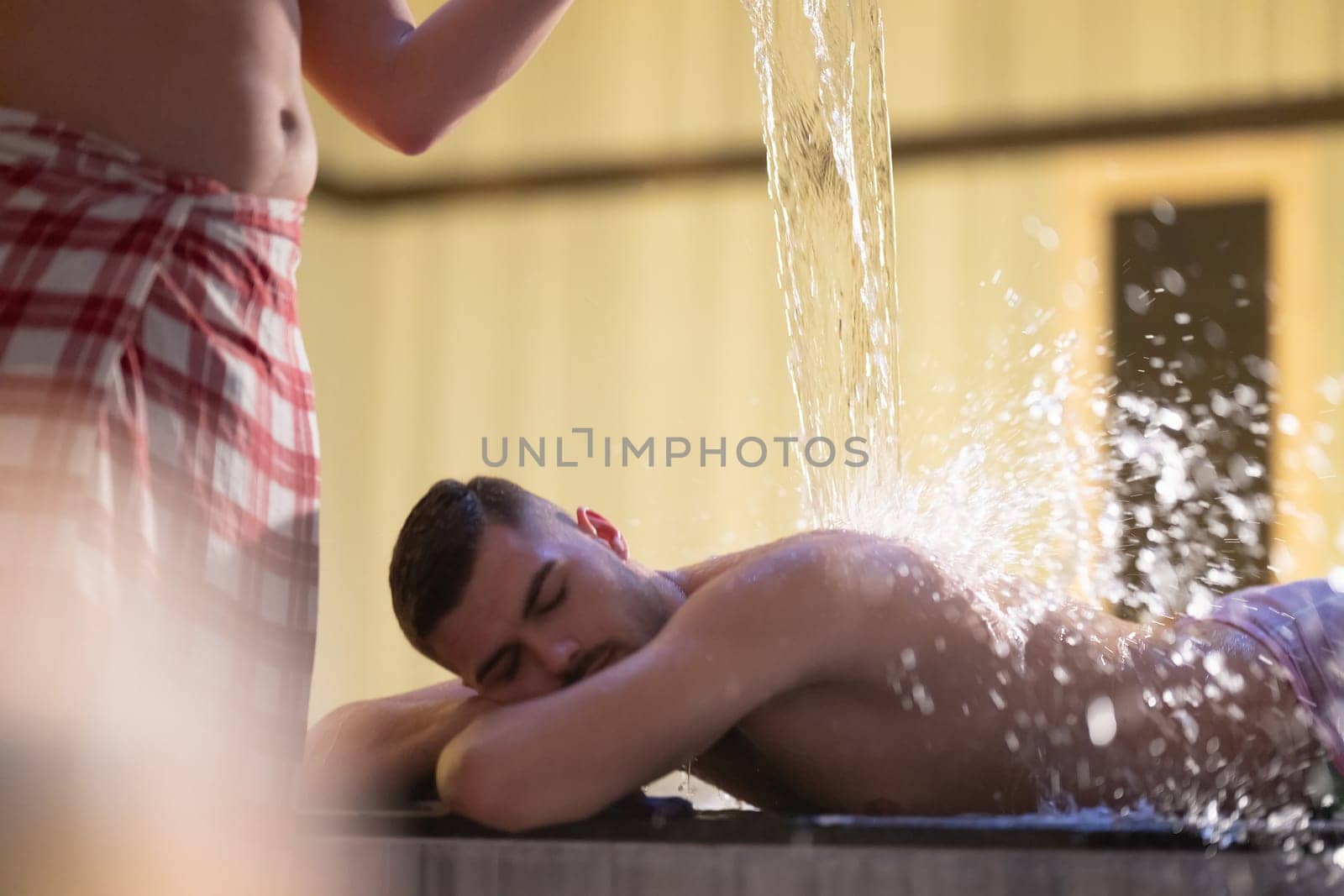 Water Treatment in Turkish Hammam.Man receiving water therapy inside a traditional Turkish hammam with ornate details.