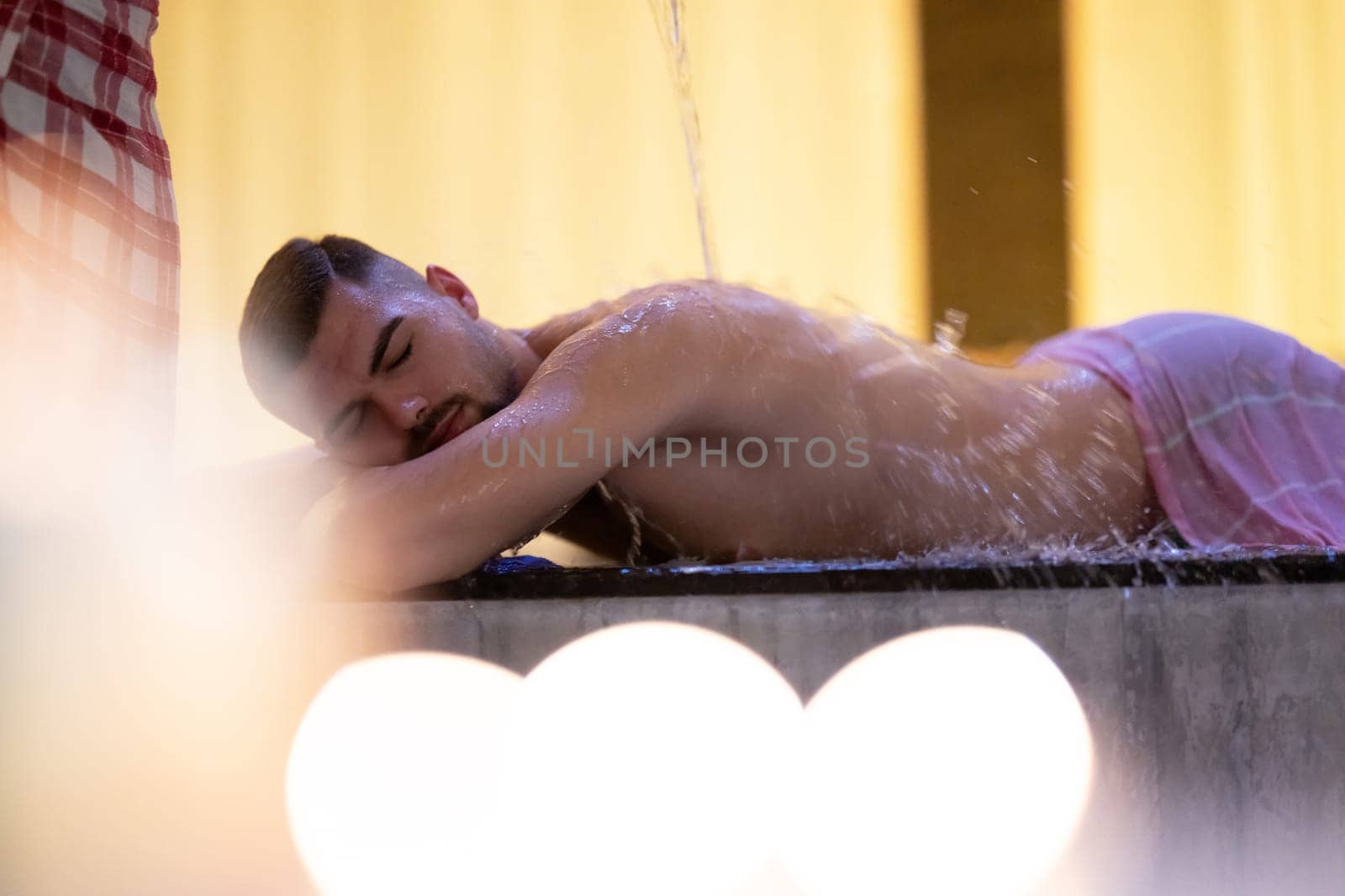 Water Treatment in Turkish Hammam.Man receiving water therapy inside a traditional Turkish hammam with ornate details.