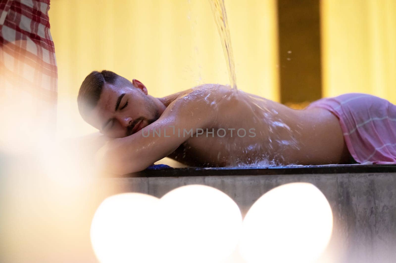 Water Treatment in Turkish Hammam.Man receiving water therapy inside a traditional Turkish hammam with ornate details.