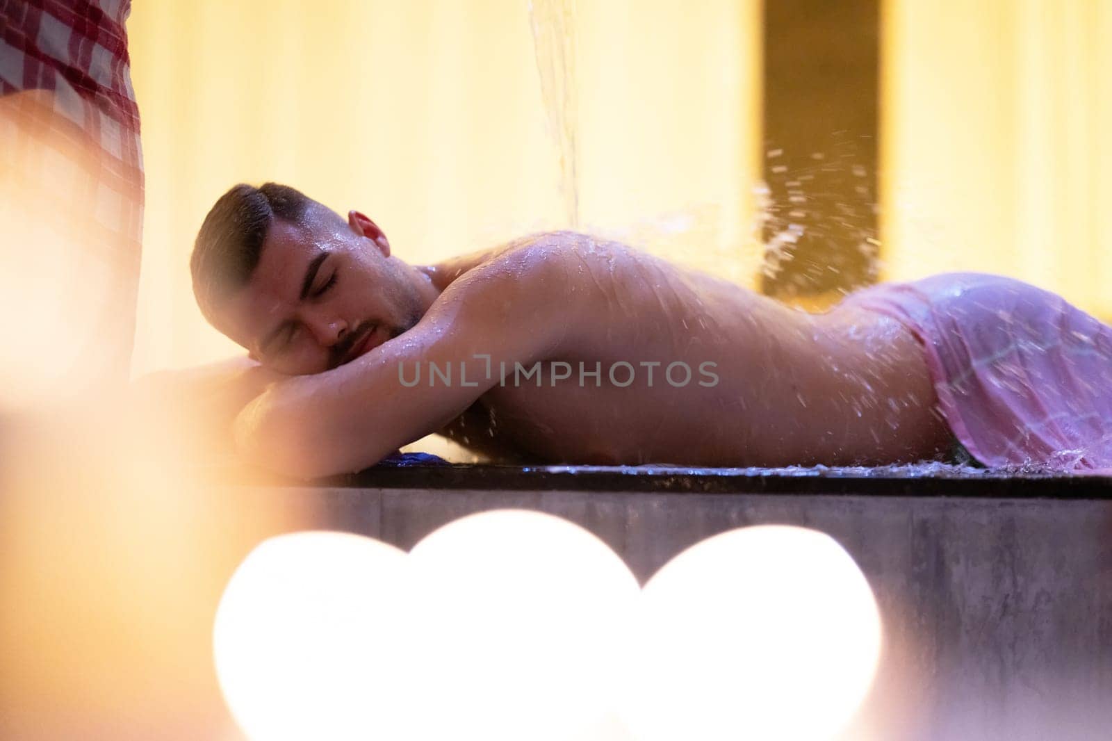 Water Treatment in Turkish Hammam.Man receiving water therapy inside a traditional Turkish hammam with ornate details.