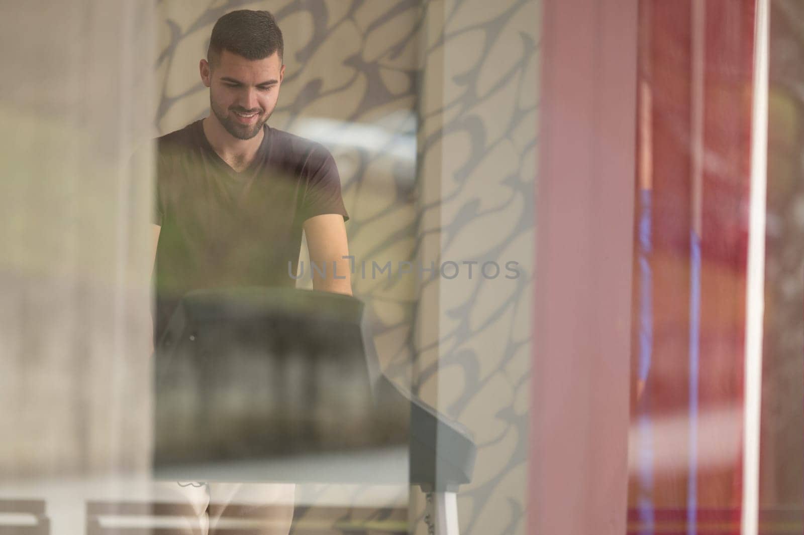 Patient visible through glass walking on treadmill as part of rehabilitation treatment.