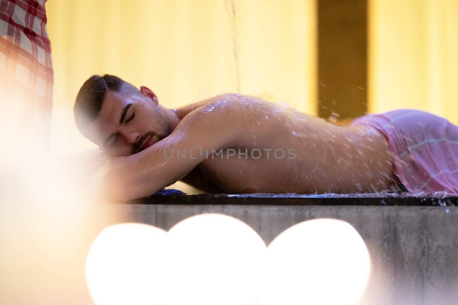 Water Treatment in Turkish Hammam.Man receiving water therapy inside a traditional Turkish hammam with ornate details.